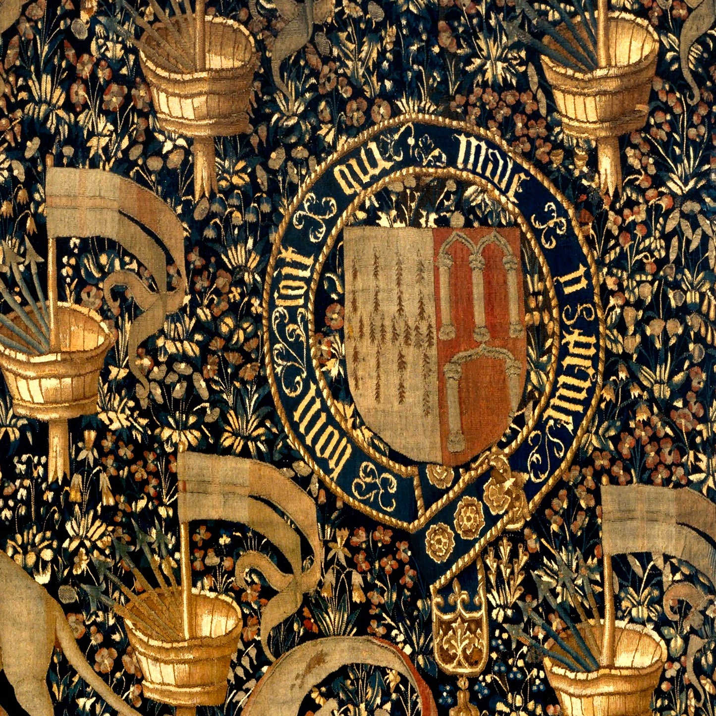 Close-up of medieval coat of arms encircled by golden text and surrounded by banners and flowers.
