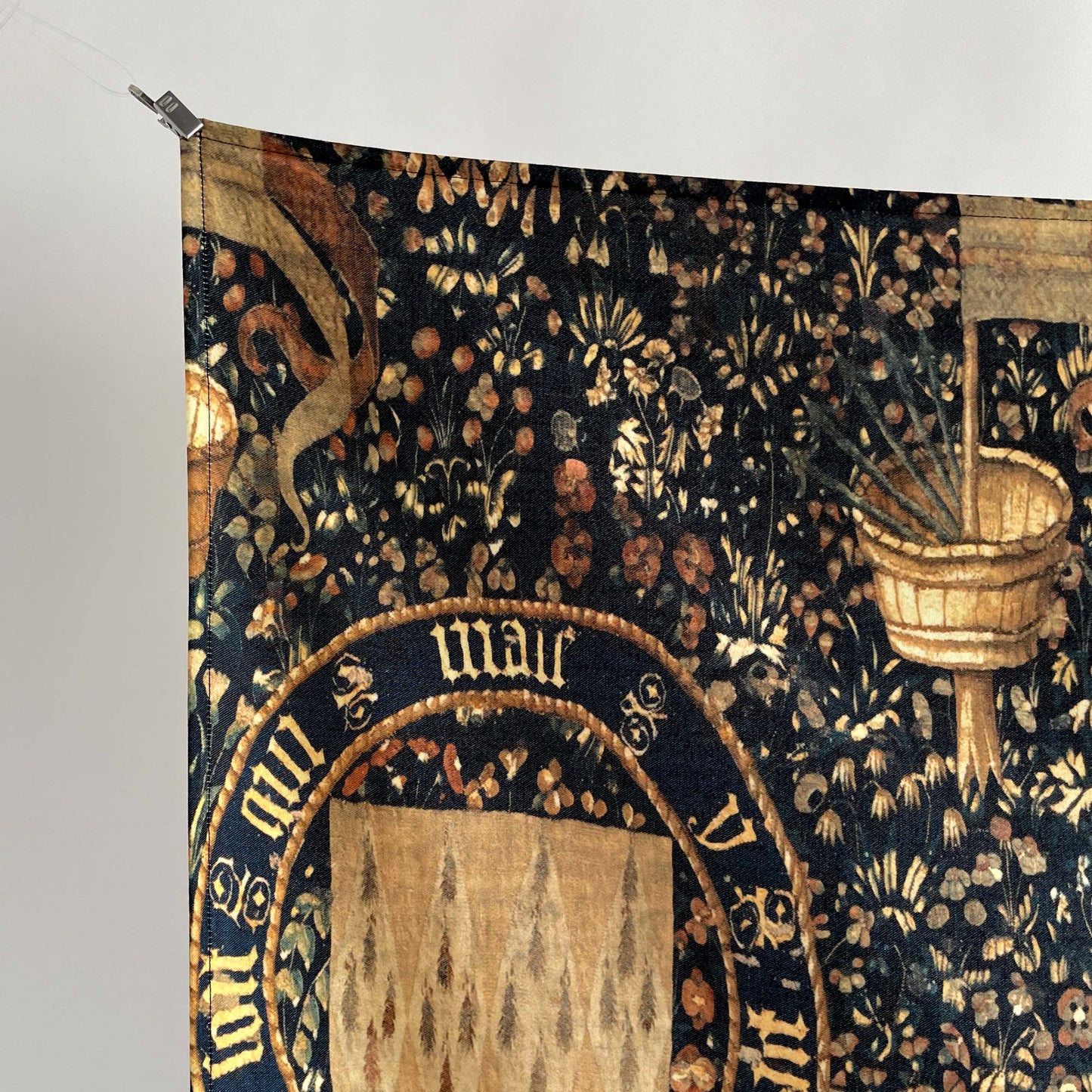 Close-up of the upper left section of the Armorial Bearings tapestry, highlighting fine medieval design and hanging clip.