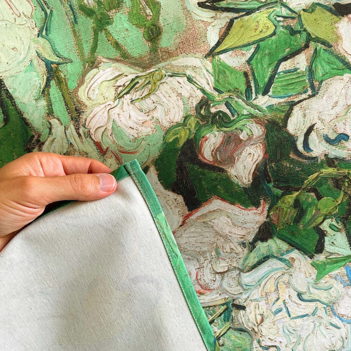 Close-up of tapestry fabric edge and stitching, held by hand, showing Van Gogh's textured brushstrokes.