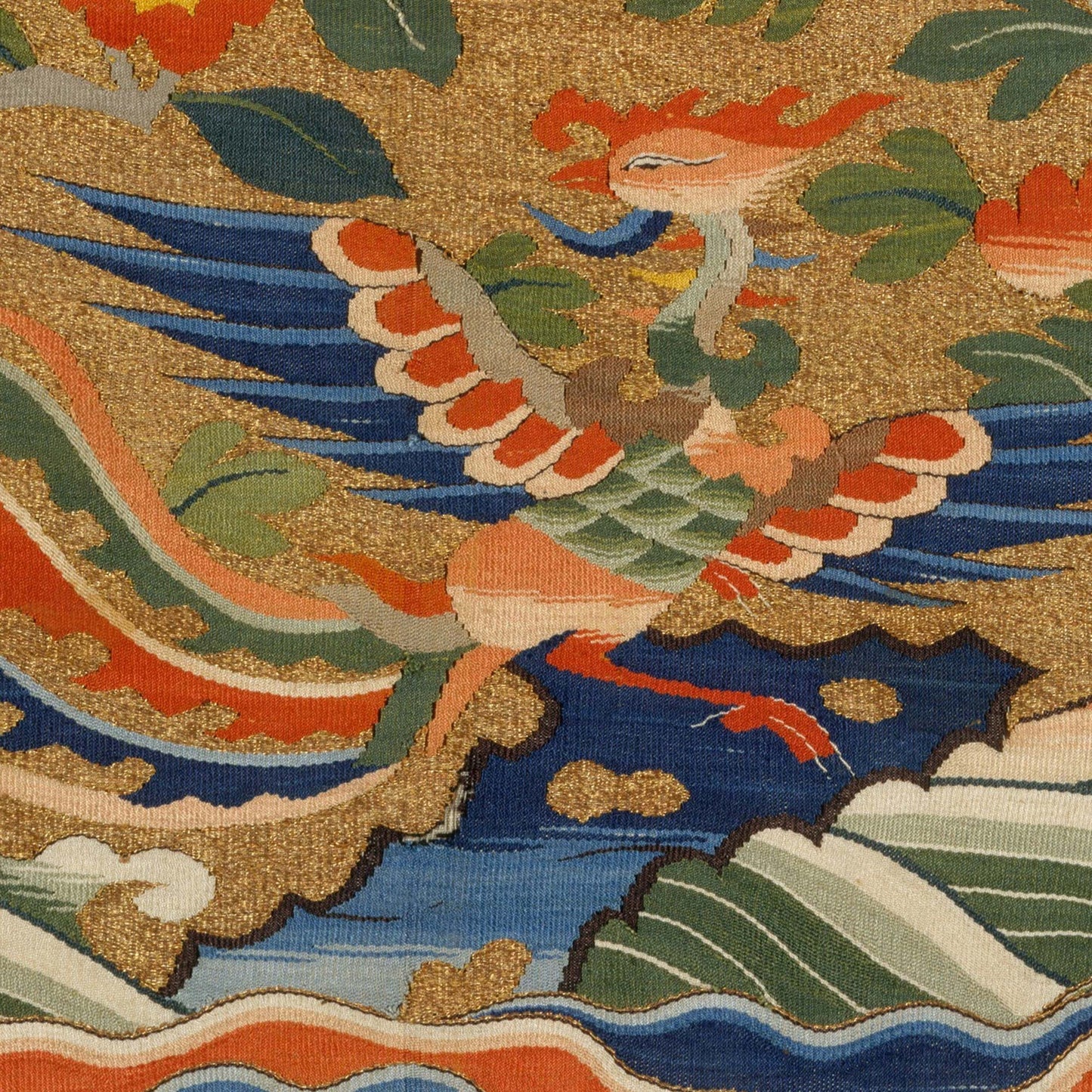 Phoenix in flight above stylized waves; jade and coral plumage edged in indigo on gold—close-up of Chinese rank badge pillow cover.