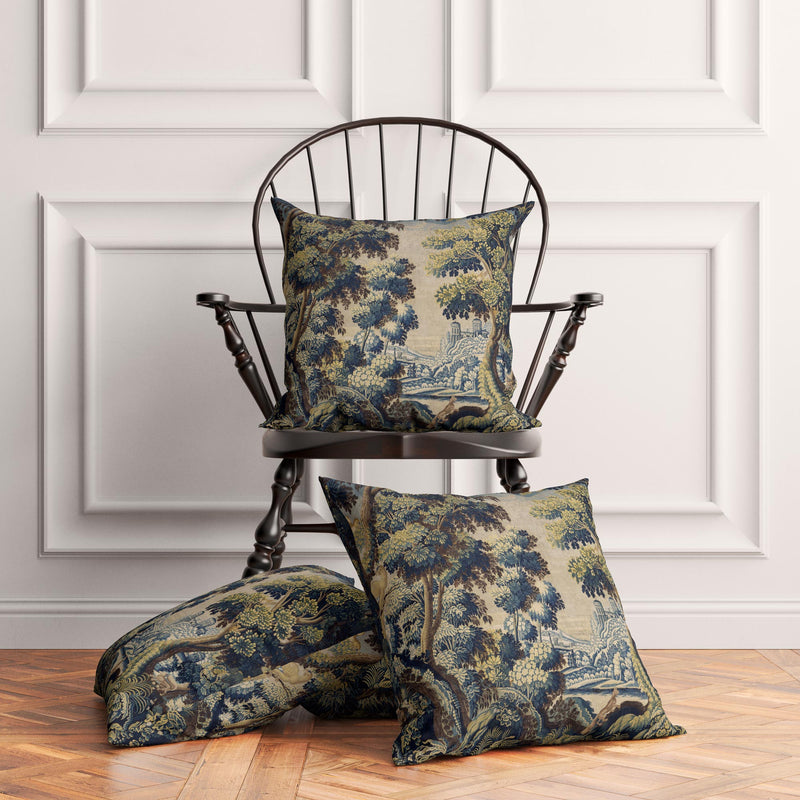 Two French Verdure Forest cushion covers styled on a wooden chair and floor in a dark academia decor scene.