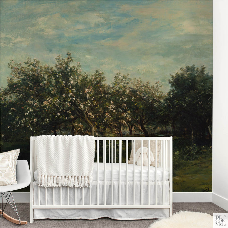 Apple blossom orchard wallpaper mural filling the wall of a light nursery behind a white crib with a plush bunny and a modern white rocking chair by Decorvm.