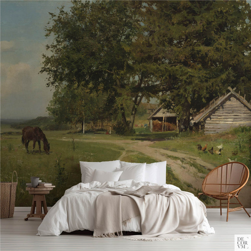 Country farm track wallpaper mural of a grazing horse in a green meadow, covering the wall behind a low bed with white linens, a wooden stool and a round rattan chair in a soft-neutral bedroom by Decorvm.