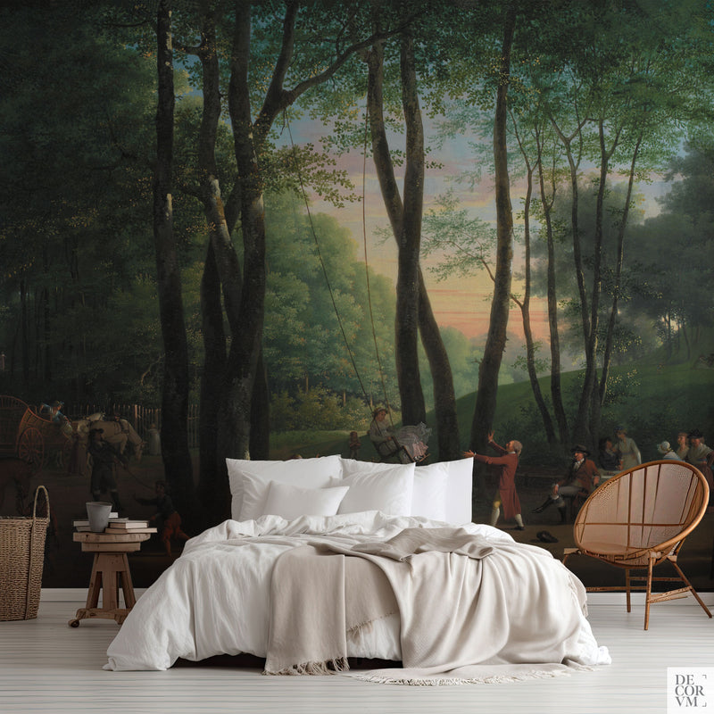 Dark forest glade wallpaper mural of tall beech trunks against an apricot sunset, covering the wall behind a low bed with white linens, a wooden stool and a round rattan chair in a soft-neutral bedroom by Decorvm.