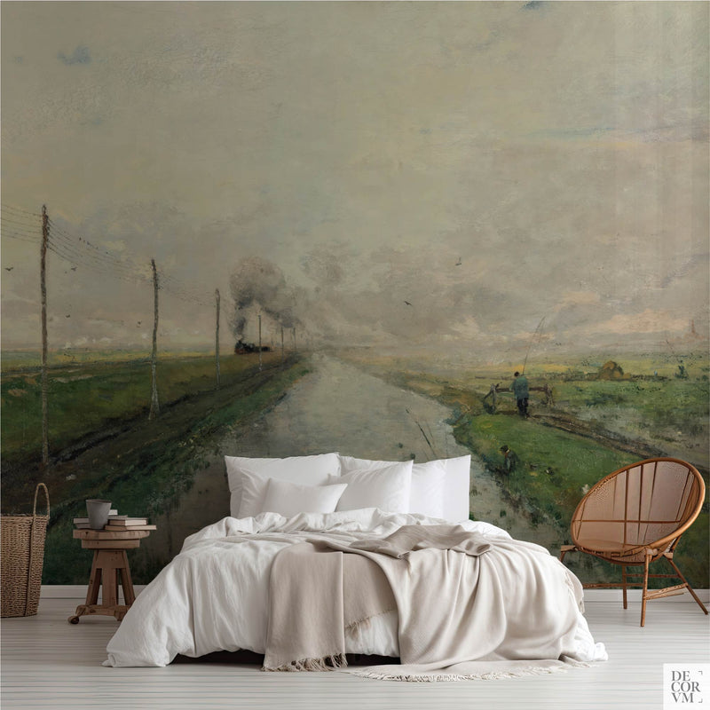 Misty canal wallpaper mural of a pale Dutch polder waterway, covering the wall behind a low bed with white linens, a wooden stool and a round rattan chair in a soft-neutral bedroom by Decorvm.