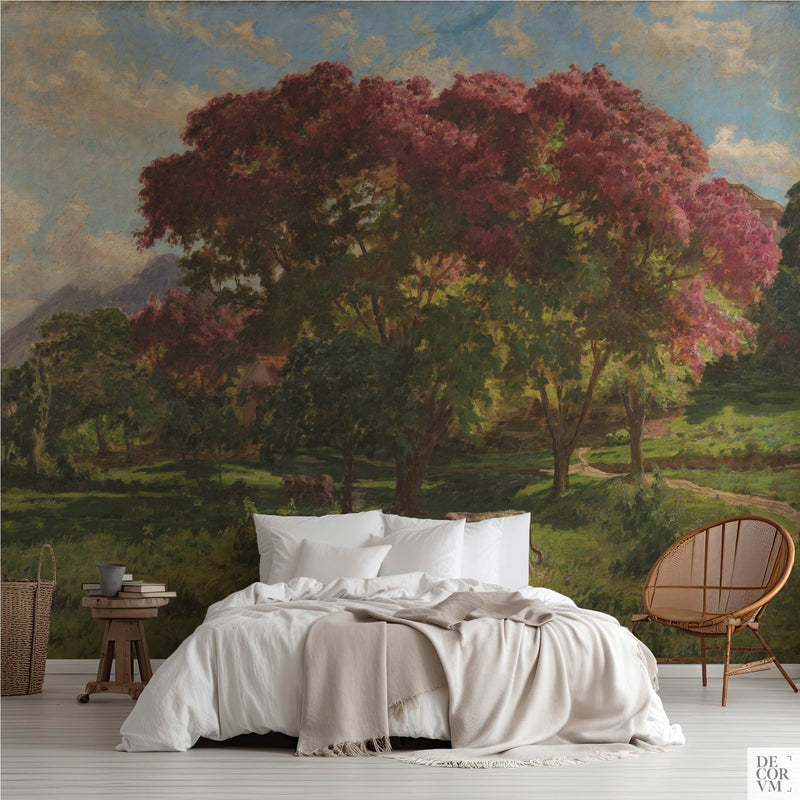 Pink blossom trees wallpaper mural of flowering sapucaia trees over green pasture, covering the wall behind a low bed with white linens, a wooden stool and a round rattan chair in a soft-neutral bedroom by Decorvm.
