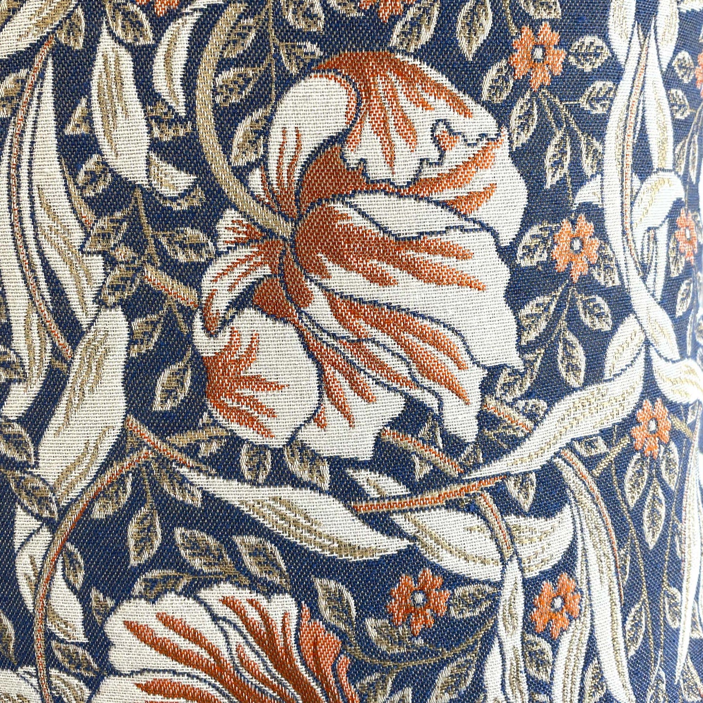 Flat detail shot of the fabric surface showing the complex interplay of blue, beige, and rust threads that form the classic Arts and Crafts Pimpernel motif.