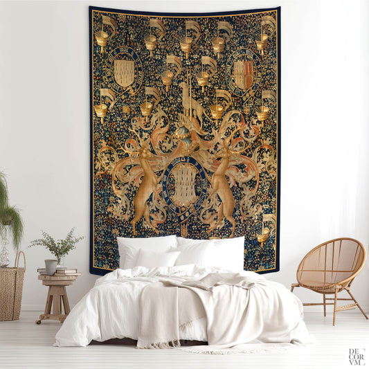 Wall tapestry with medieval armorial bearings and golden details, displayed above a bed in a minimalist bedroom.
