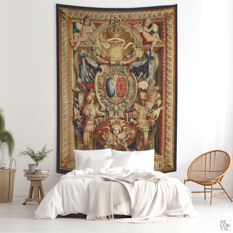Large Portière of the Chariot of Triumph wall tapestry above a bed in a moody bedroom — French baroque heraldic design with crown, cherubs, and banners.
