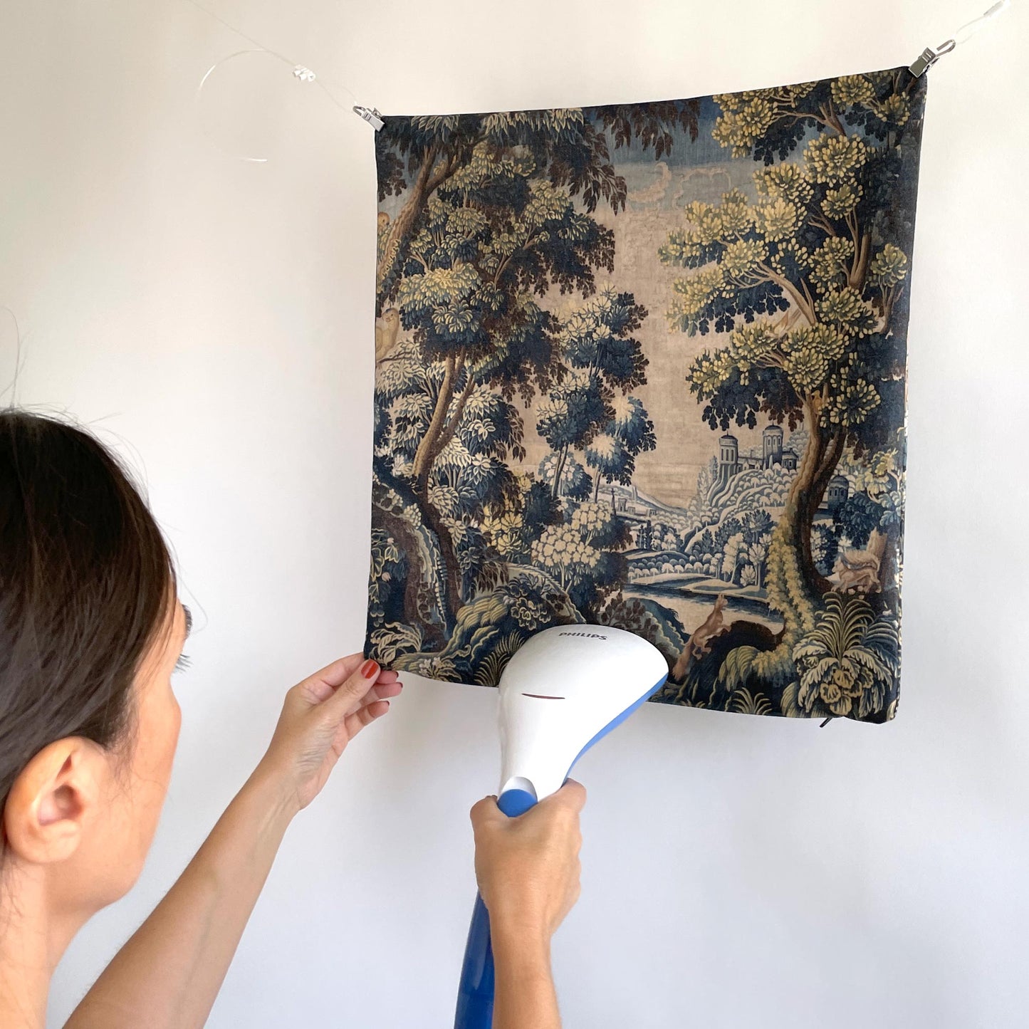 Hanging verdure tapestry cushion being steamed showing soft fabric texture and forest print vintage reproduction by Decorvm