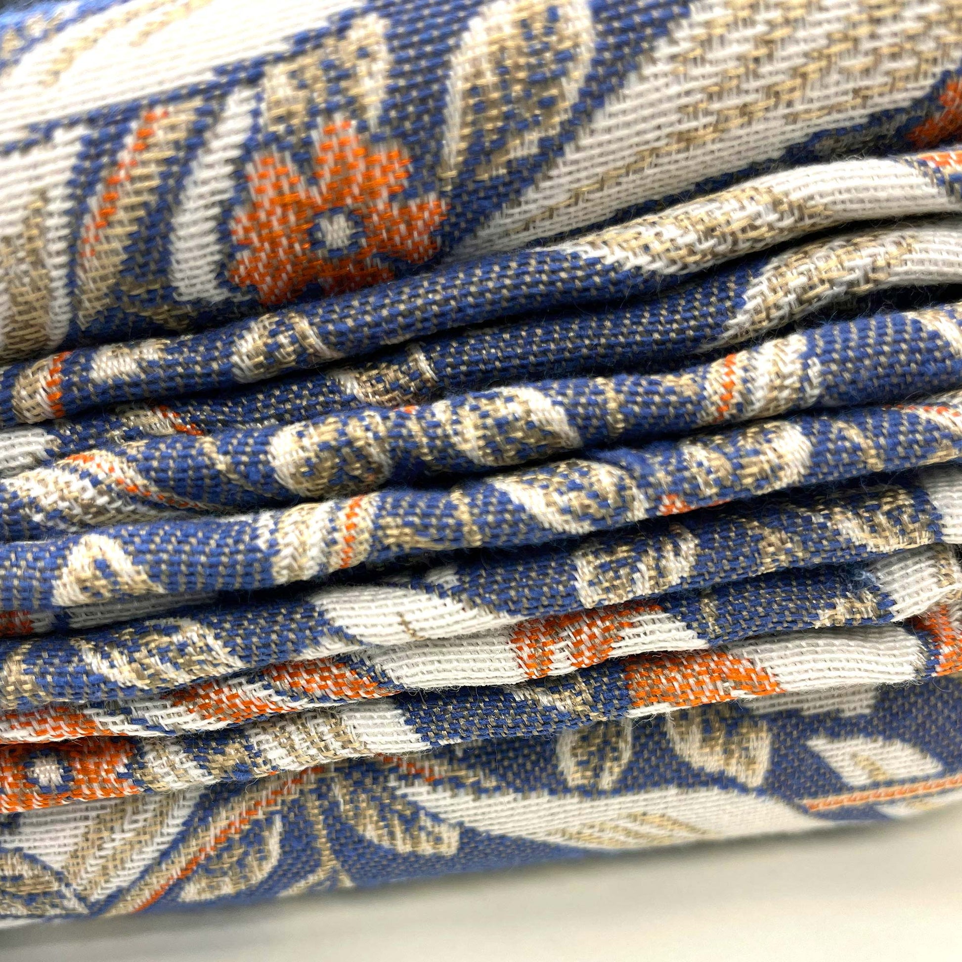 Edge view of folded Pimpernel jacquard showing dense weave, layered leaves and small rust flowers.