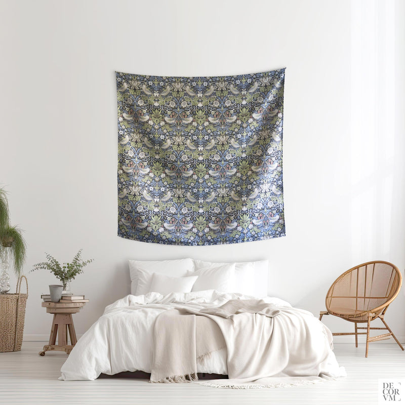 William Morris Strawberry Thief wall tapestry above a white bed in a bright bedroom — 1883 Arts and Crafts woven jacquard in layered blues and sage by Decorvm.