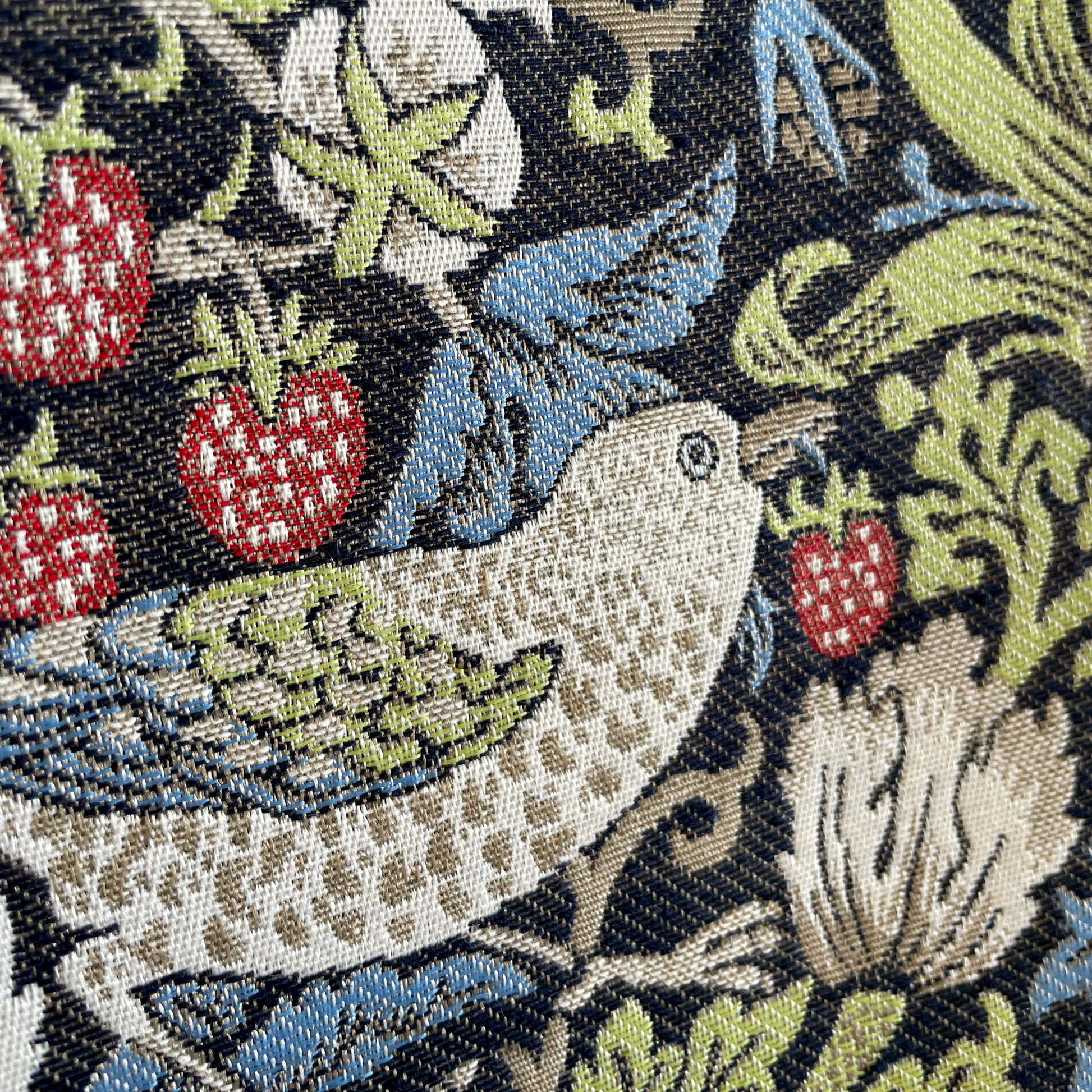 Macro of bird and strawberry motif highlighting the textured jacquard weave and color detail.