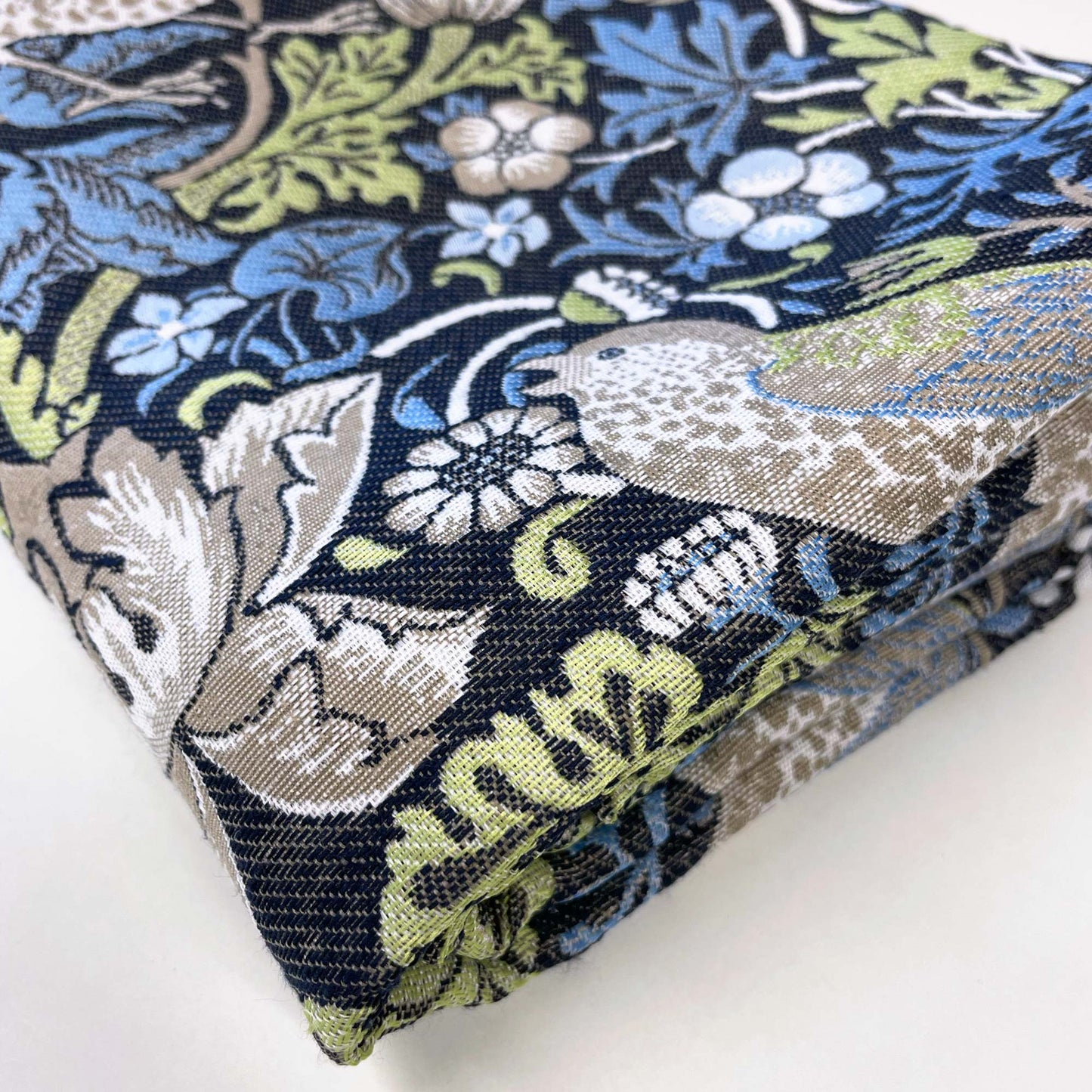 Folded Strawberry Thief tapestry in blue, sage, and taupe tones, showing dense weave and tidy finish.