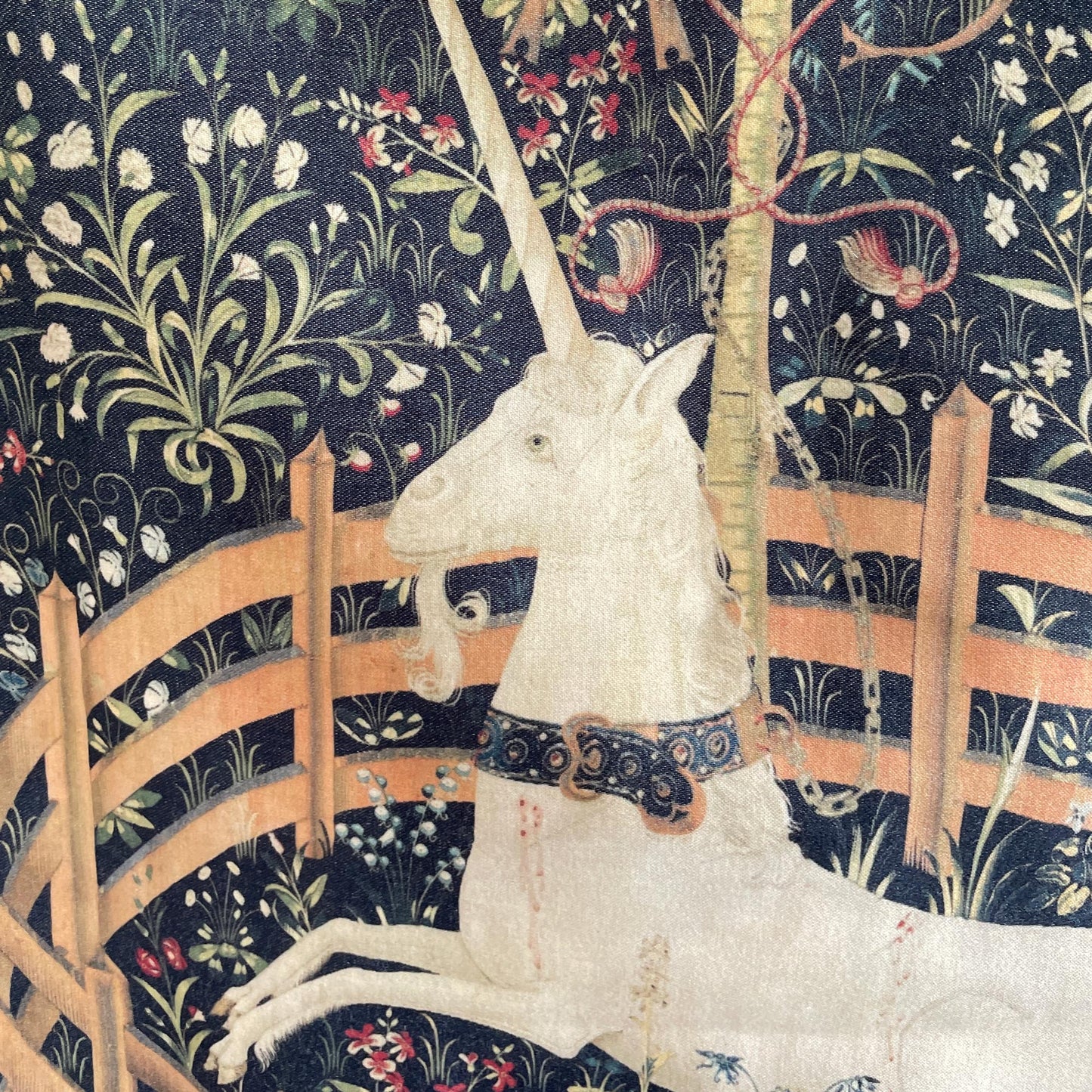 Close-up of the printed fabric on the Unicorn in Captivity cushion cover, revealing the tethered white unicorn and historic millefleur background.
