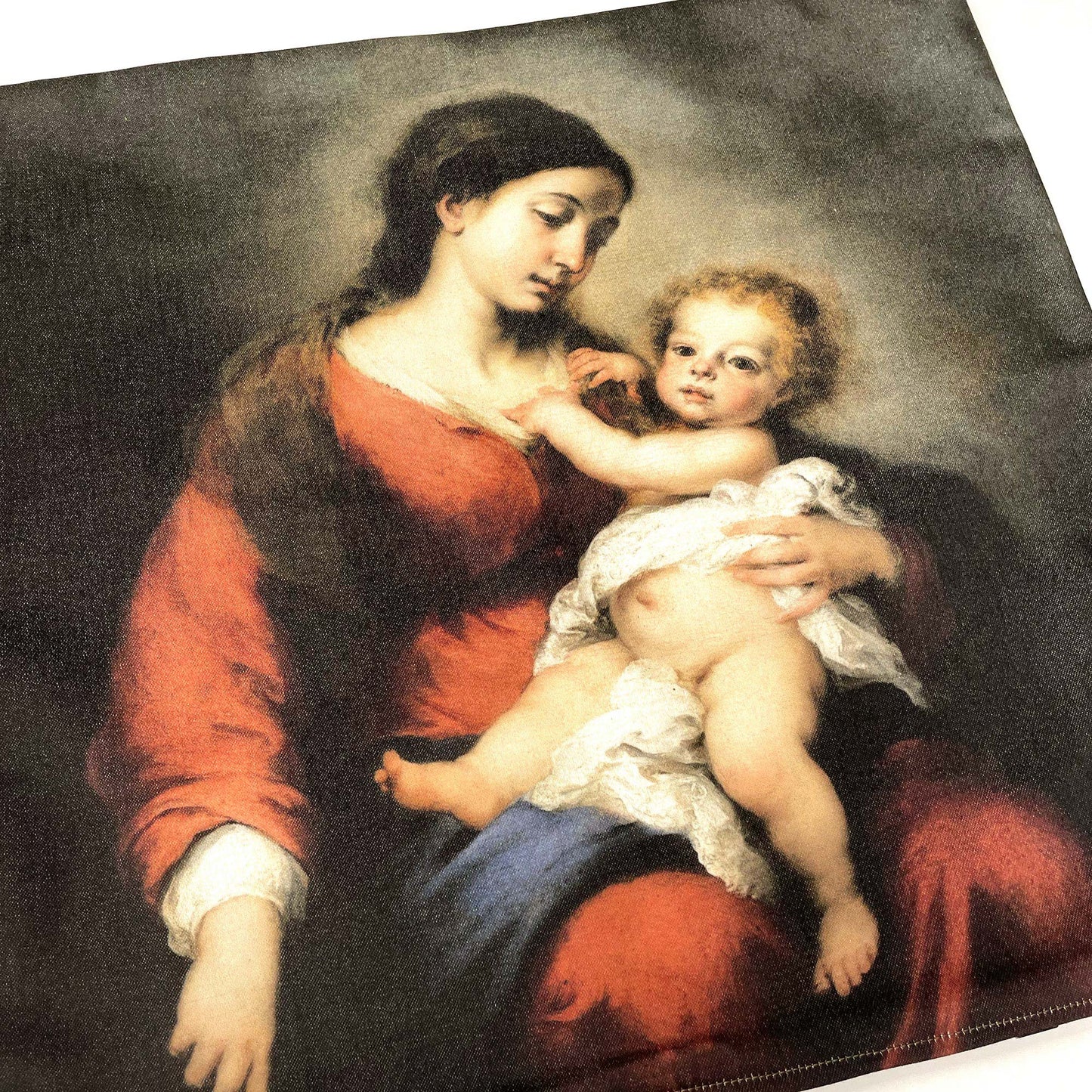 Flat lay of the Murillo Virgin and Child pillow cover showing the warm Baroque palette of red, brown, and earth tones.