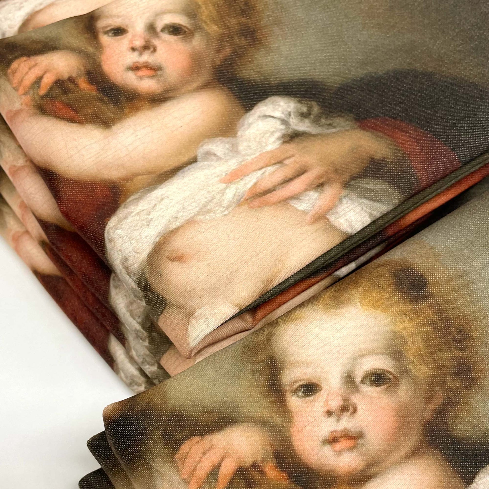 Folded stack of Murillo Virgin and Child pillow covers showing the printed surface and fabric finish.
