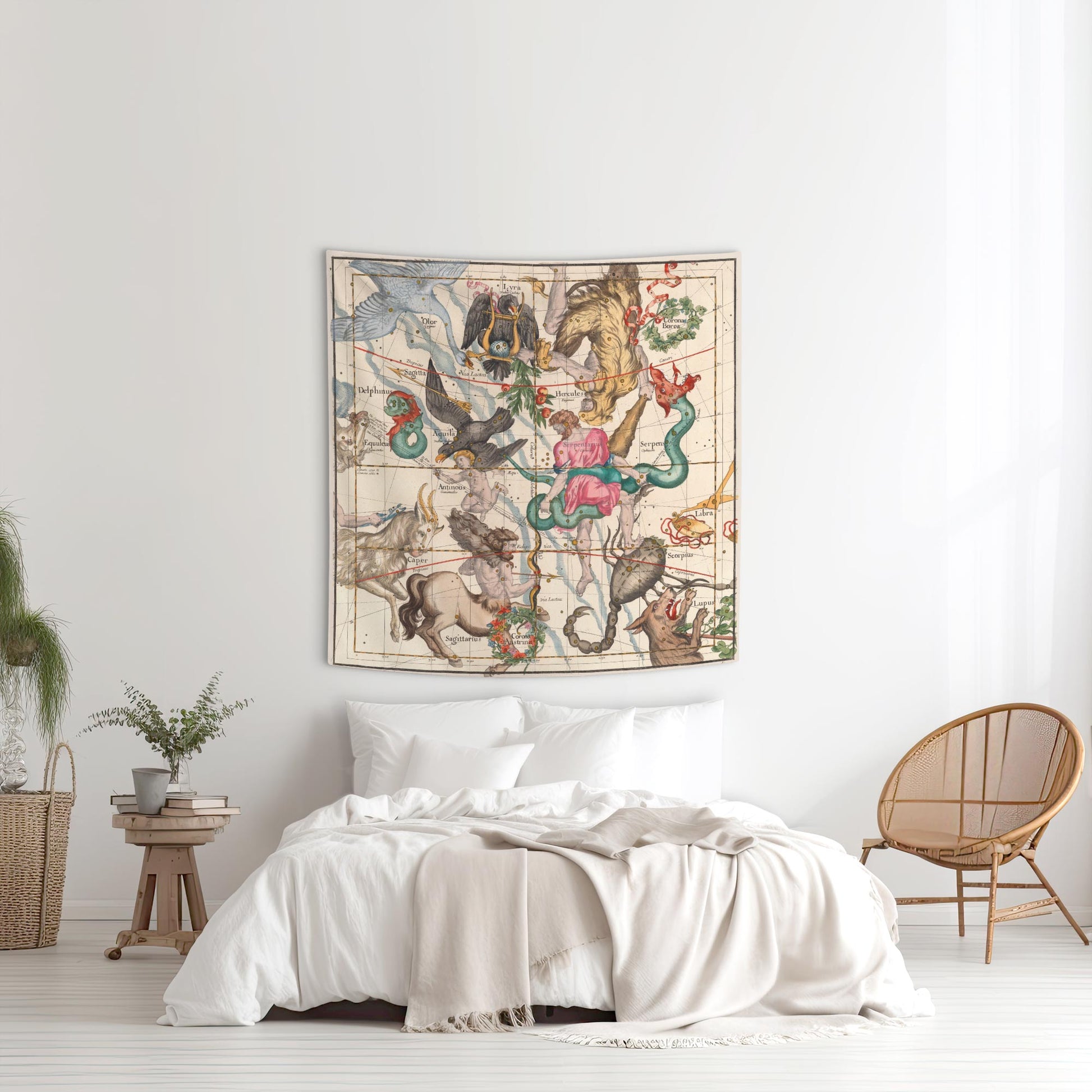 Hercules and Sagittarius vintage star chart tapestry displayed above a white bed with a wicker chair in a bright bedroom.