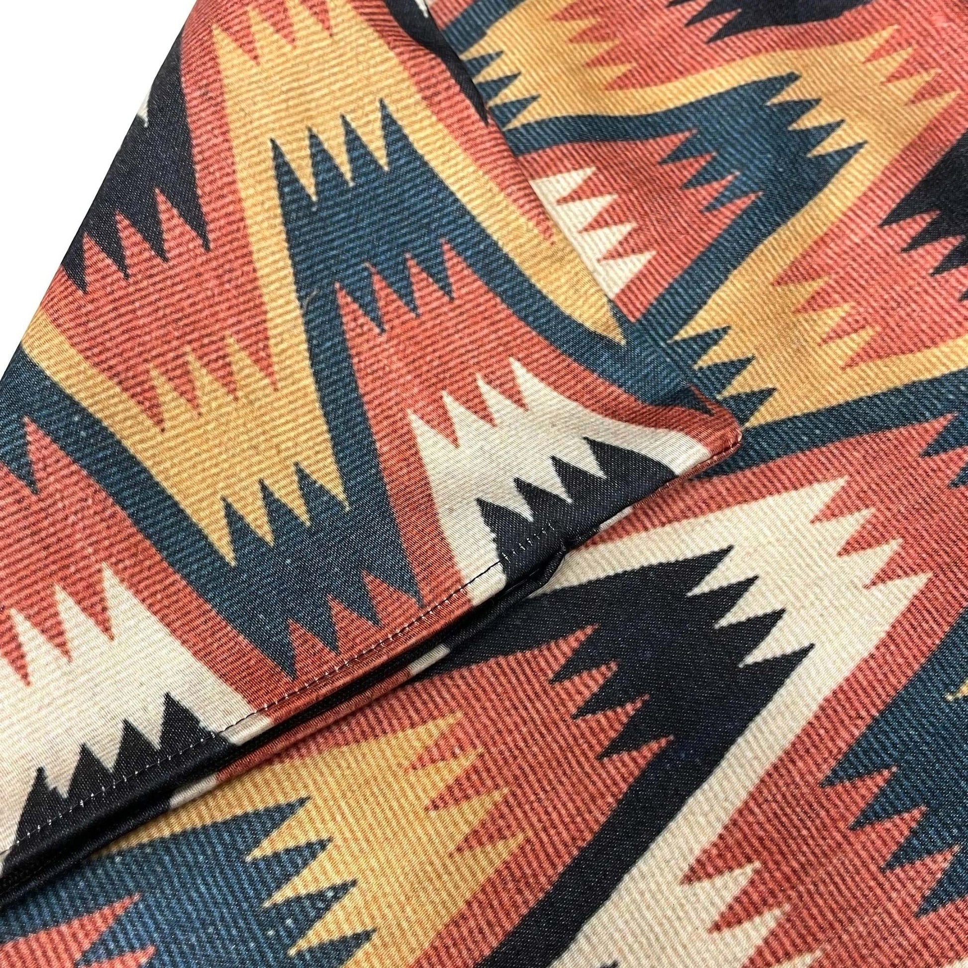 Folded Swedish folk zigzag cushion cover showing the rust, navy, ochre, and cream zigzag repeat.