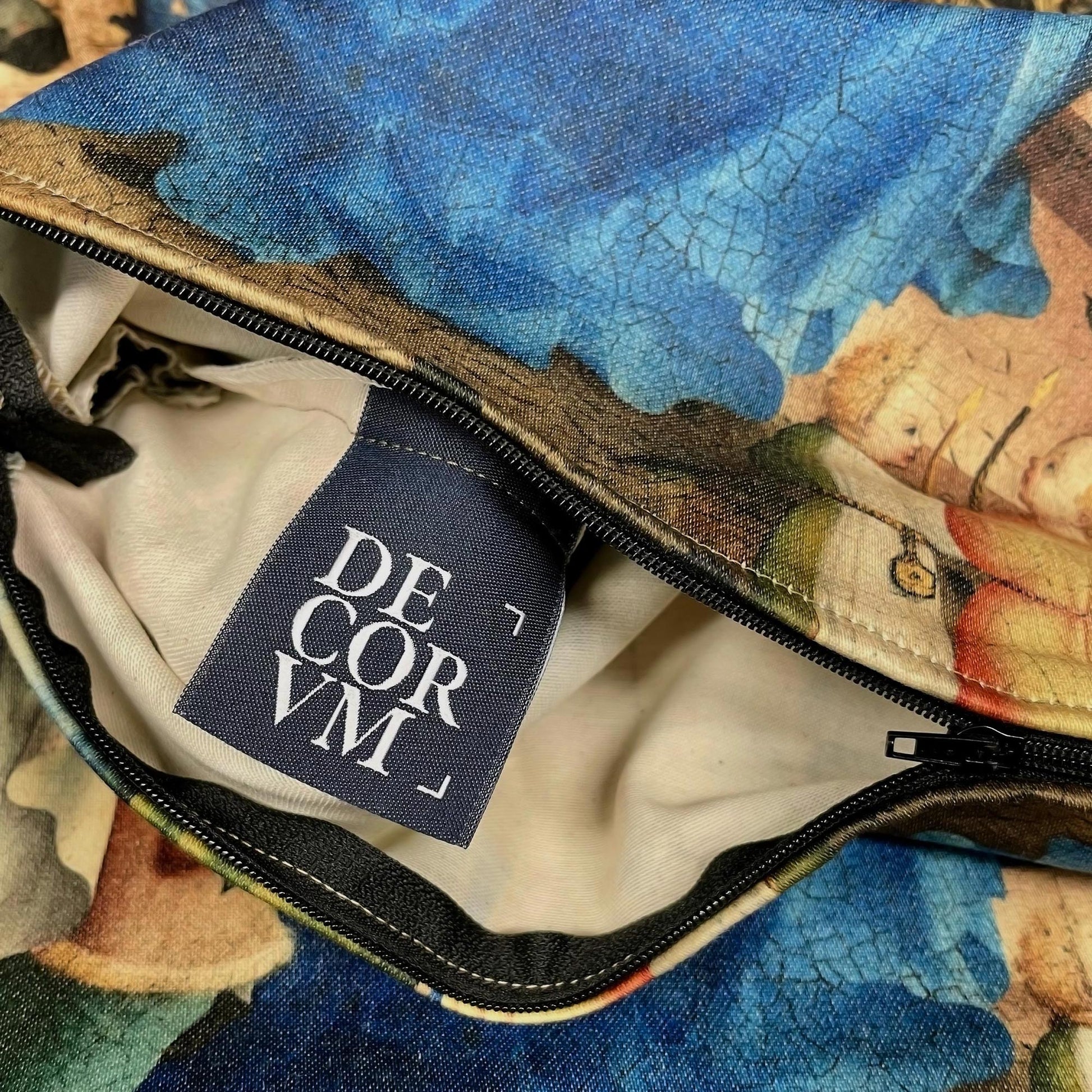 Open black zipper revealing the inner lining and Decorvm woven brand tag on the medieval Virgin Mary cushion cover.