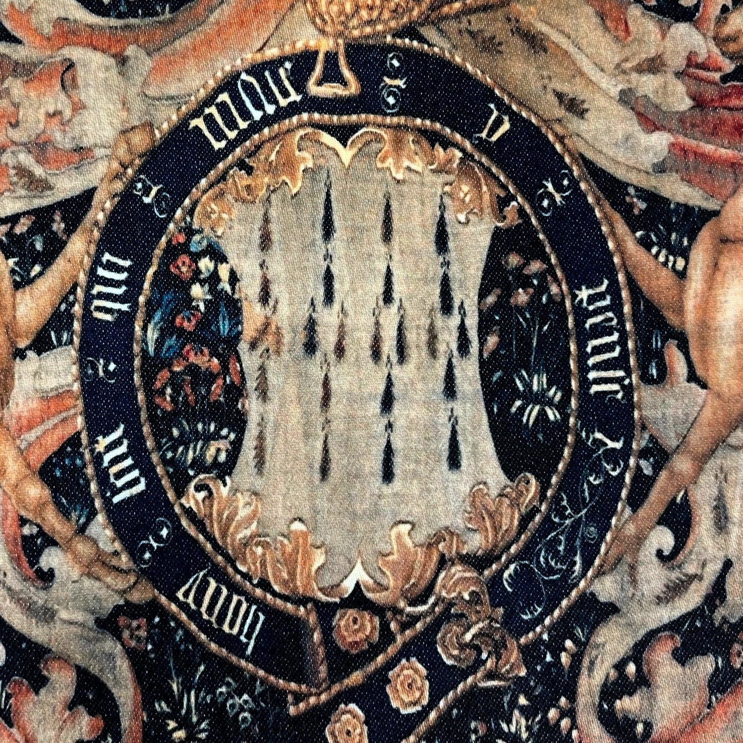 Close-up of the central coat of arms and inscribed garter — design detail from the late 15th-century Lord Dynham heraldic tapestry.