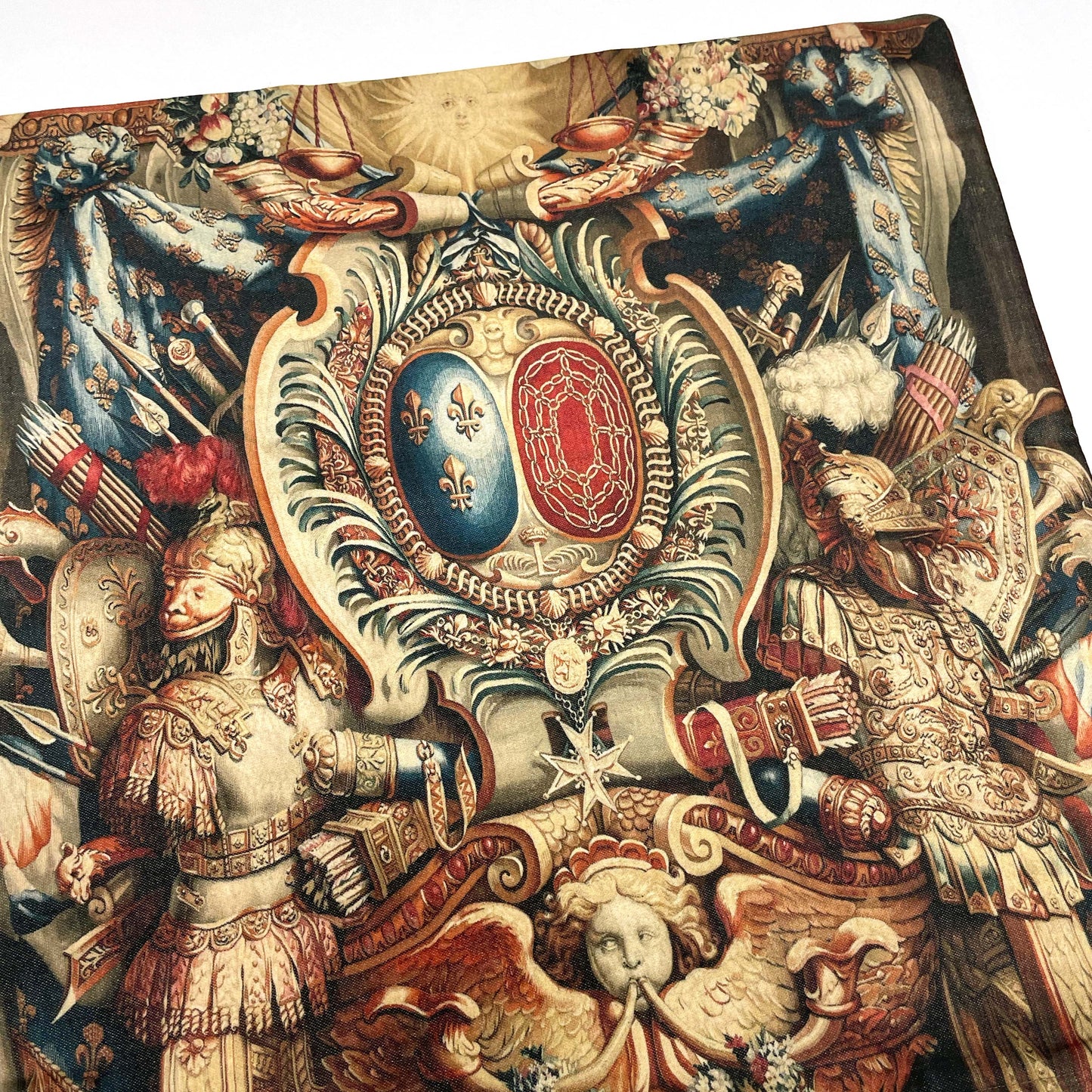 Flat lay detail of the Portière Chariot of Triumph cushion cover showing royal crown, fleur-de-lis, and classical military armor in red and gold.