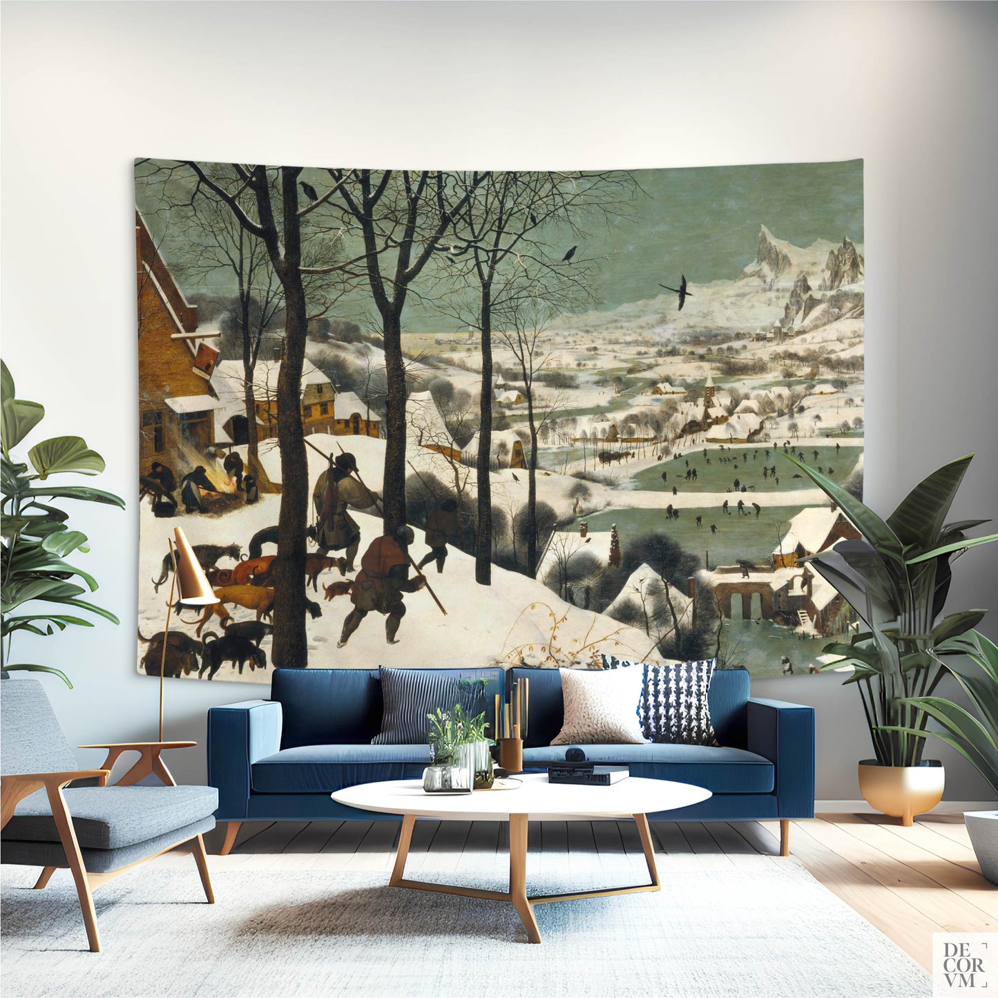 Bruegel "Hunters in the Snow" wall tapestry in modern living room with navy sofa; winter village panorama statement art.