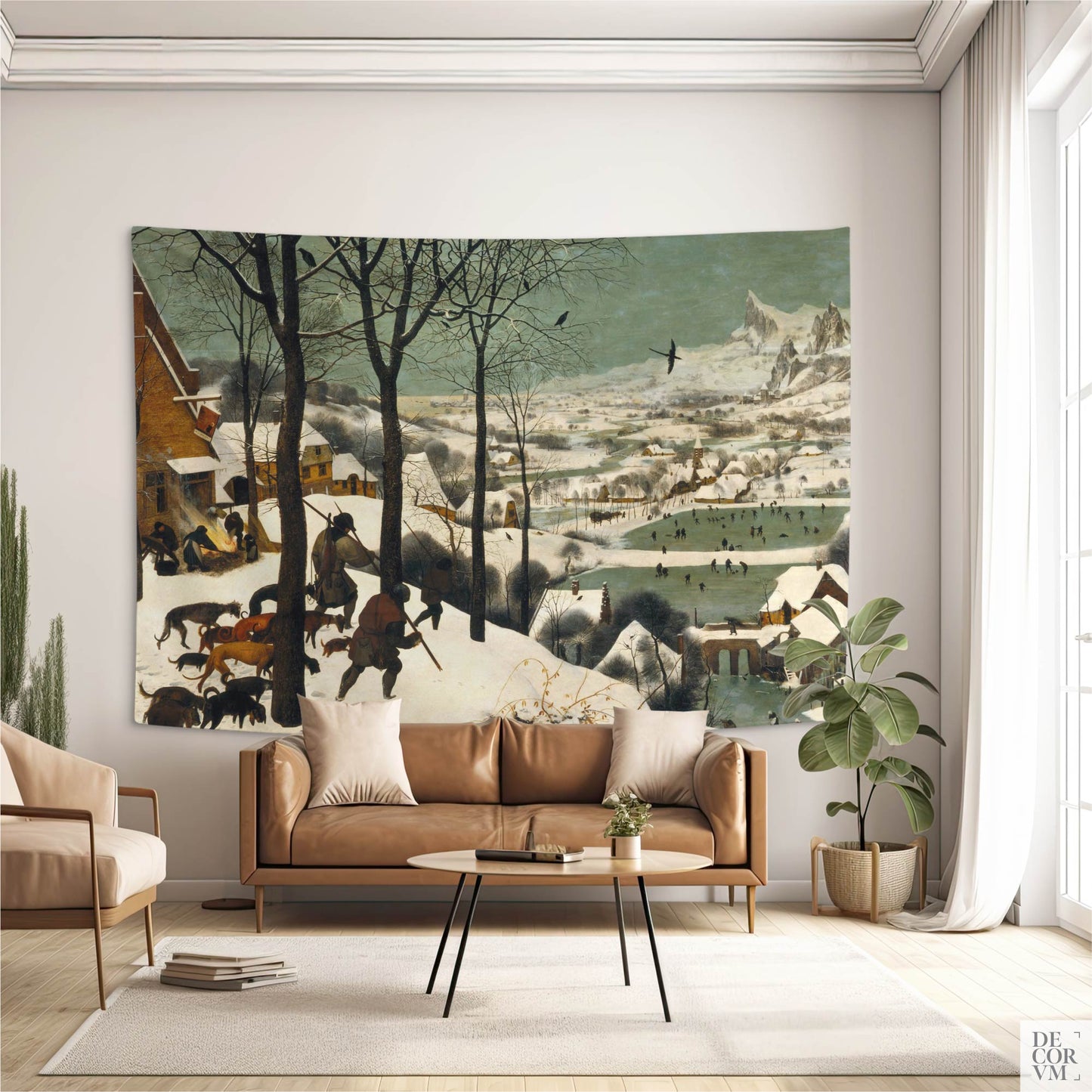 "Hunters in the Snow" wall tapestry over tan leather sofa; Bruegel winter landscape adds old-world warmth to a neutral living room.