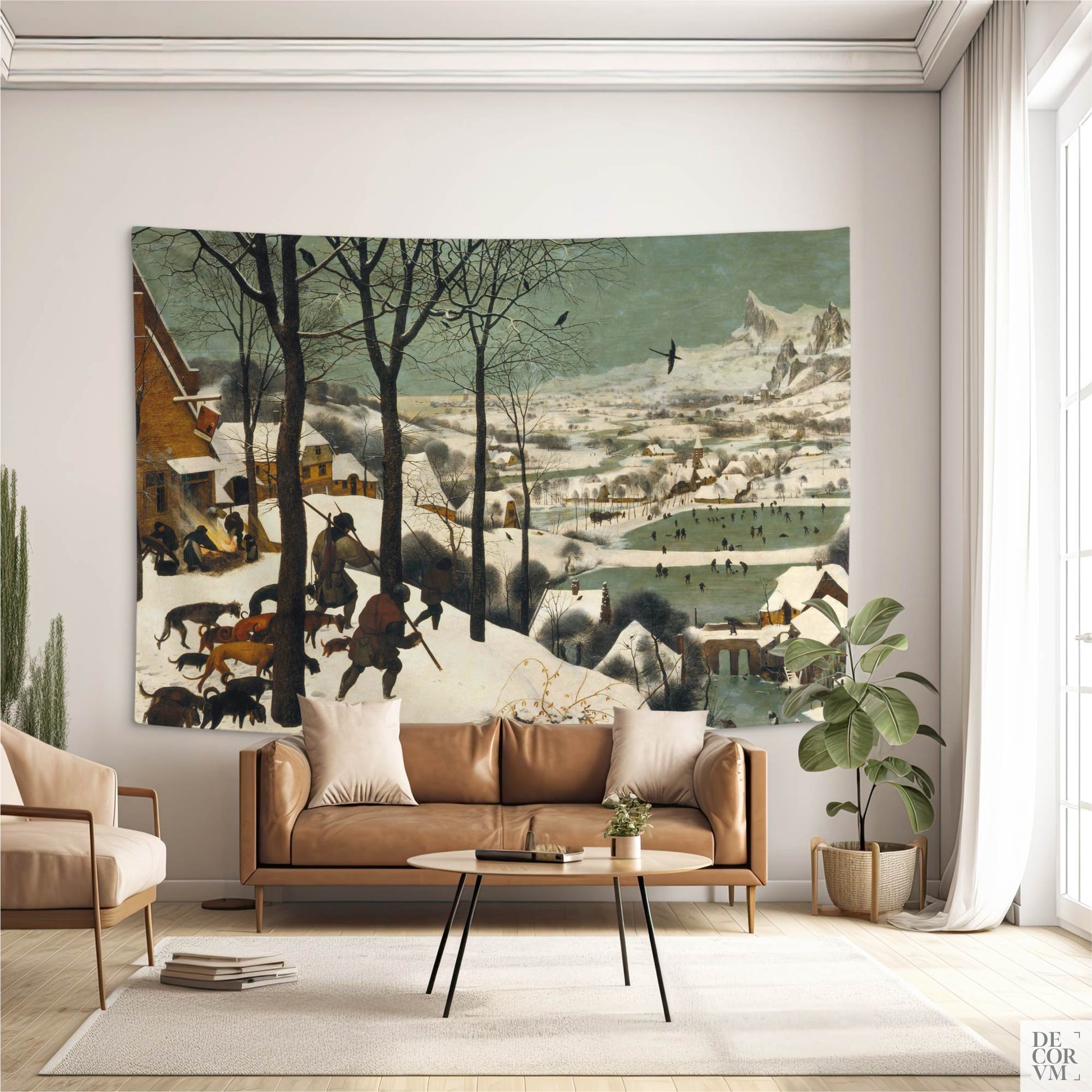 "Hunters in the Snow" wall tapestry over tan leather sofa; Bruegel winter landscape adds old-world warmth to a neutral living room.