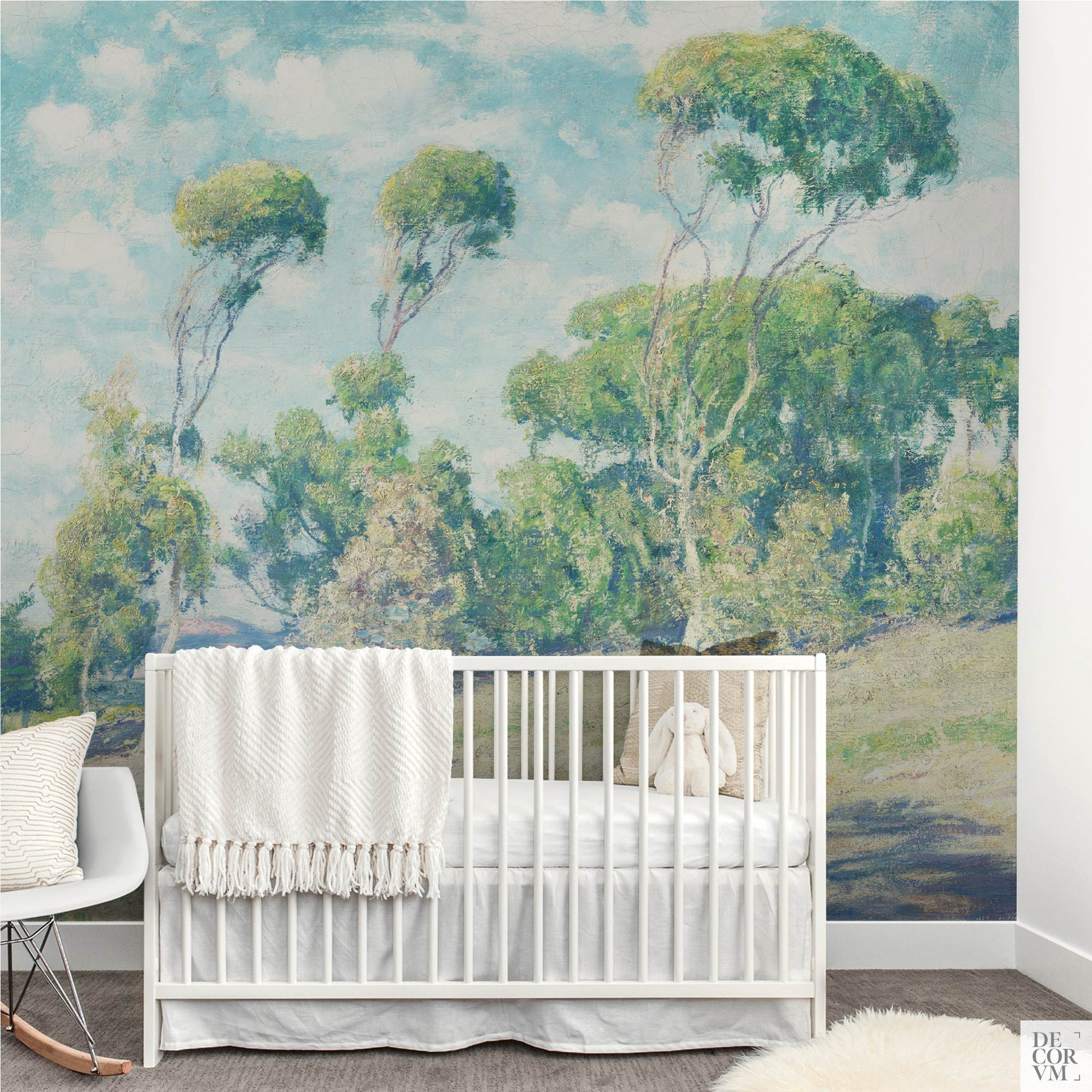 Eucalyptus coastal wallpaper mural in a calming nursery — airy blue skies and soft green trees behind a white baby crib for peaceful baby room decor