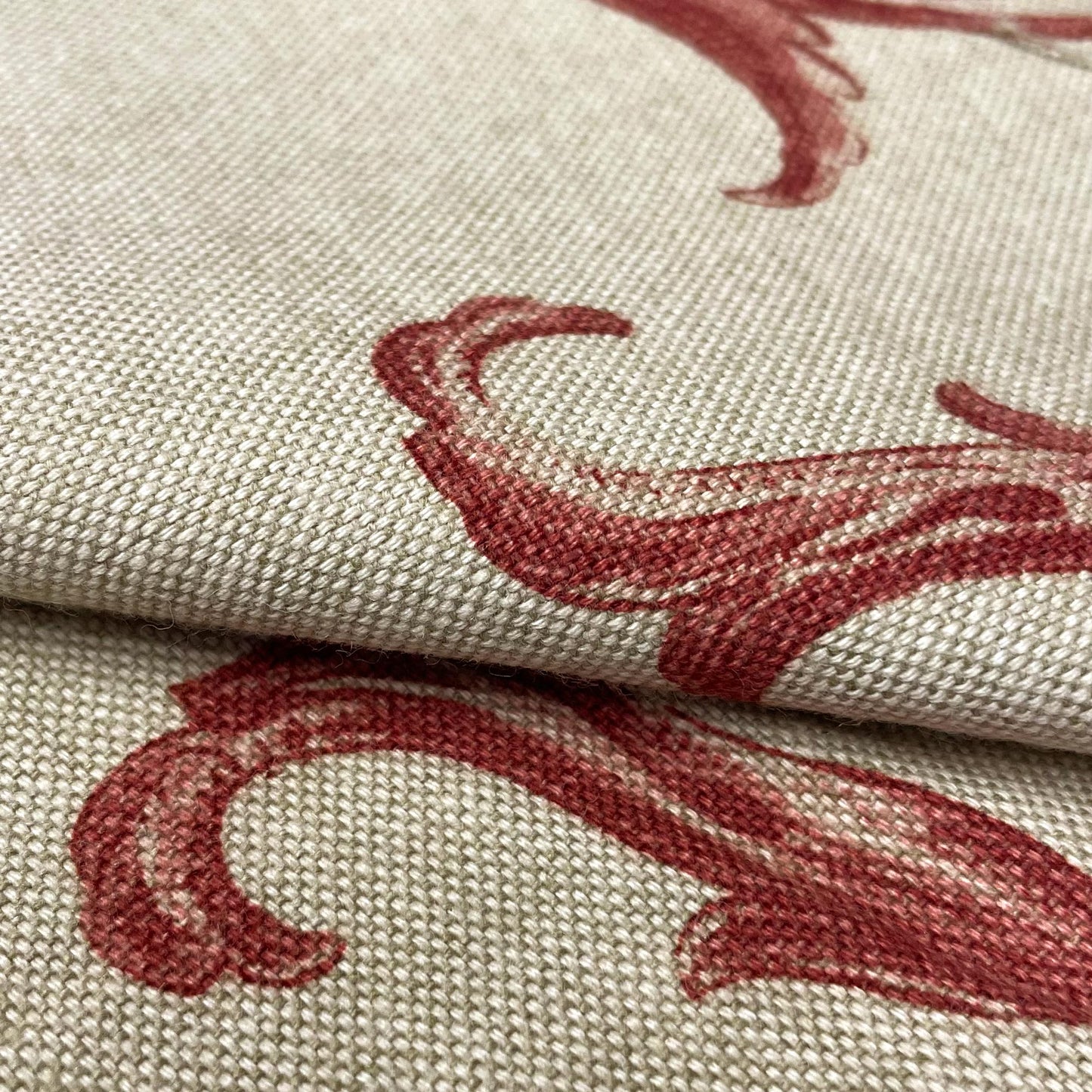 Detailed macro shot of a woven textile revealing the intricate texture of the fabric and the rich burgundy red ink of the printed botanical design.