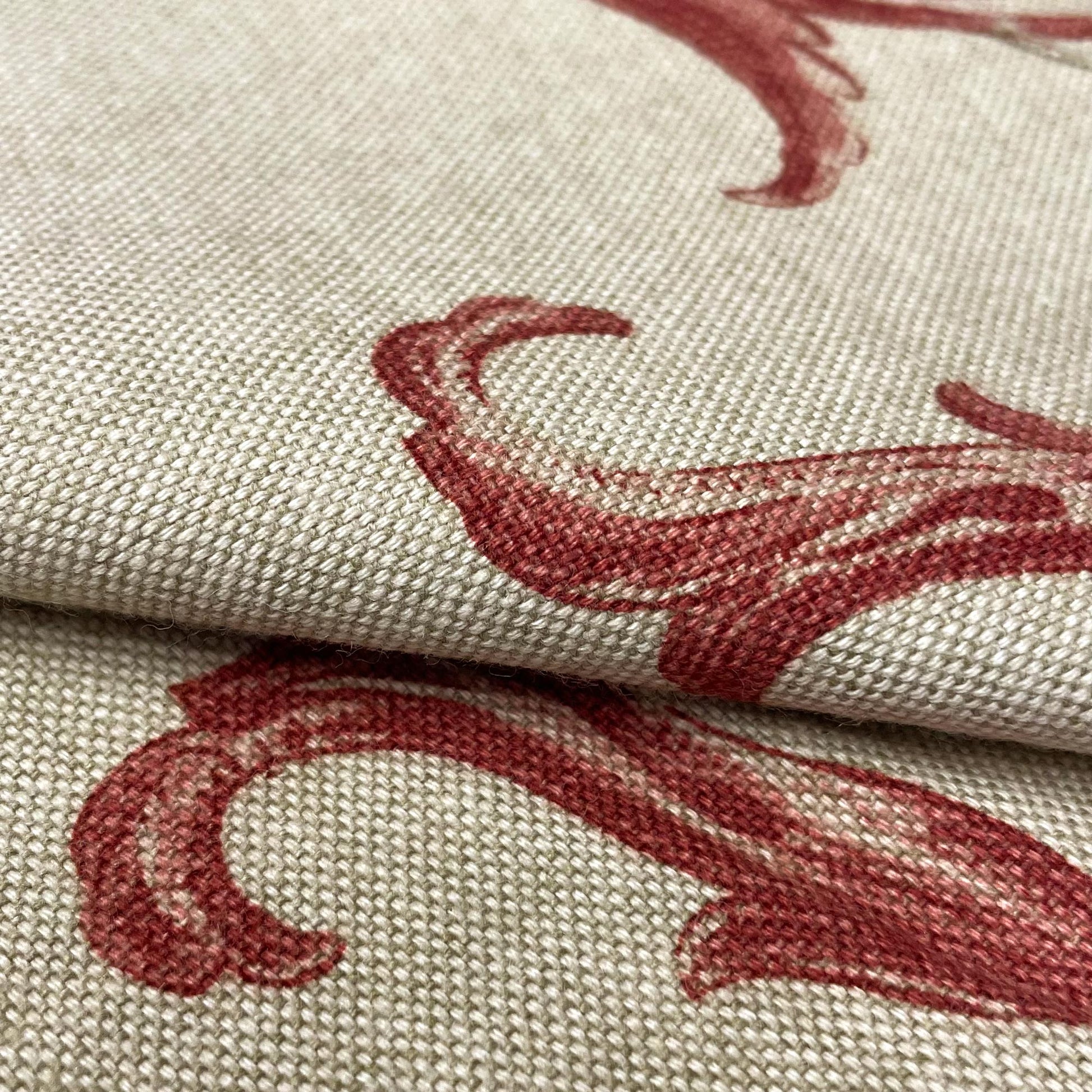Detailed macro shot of a woven textile revealing the intricate texture of the fabric and the rich burgundy red ink of the printed botanical design.