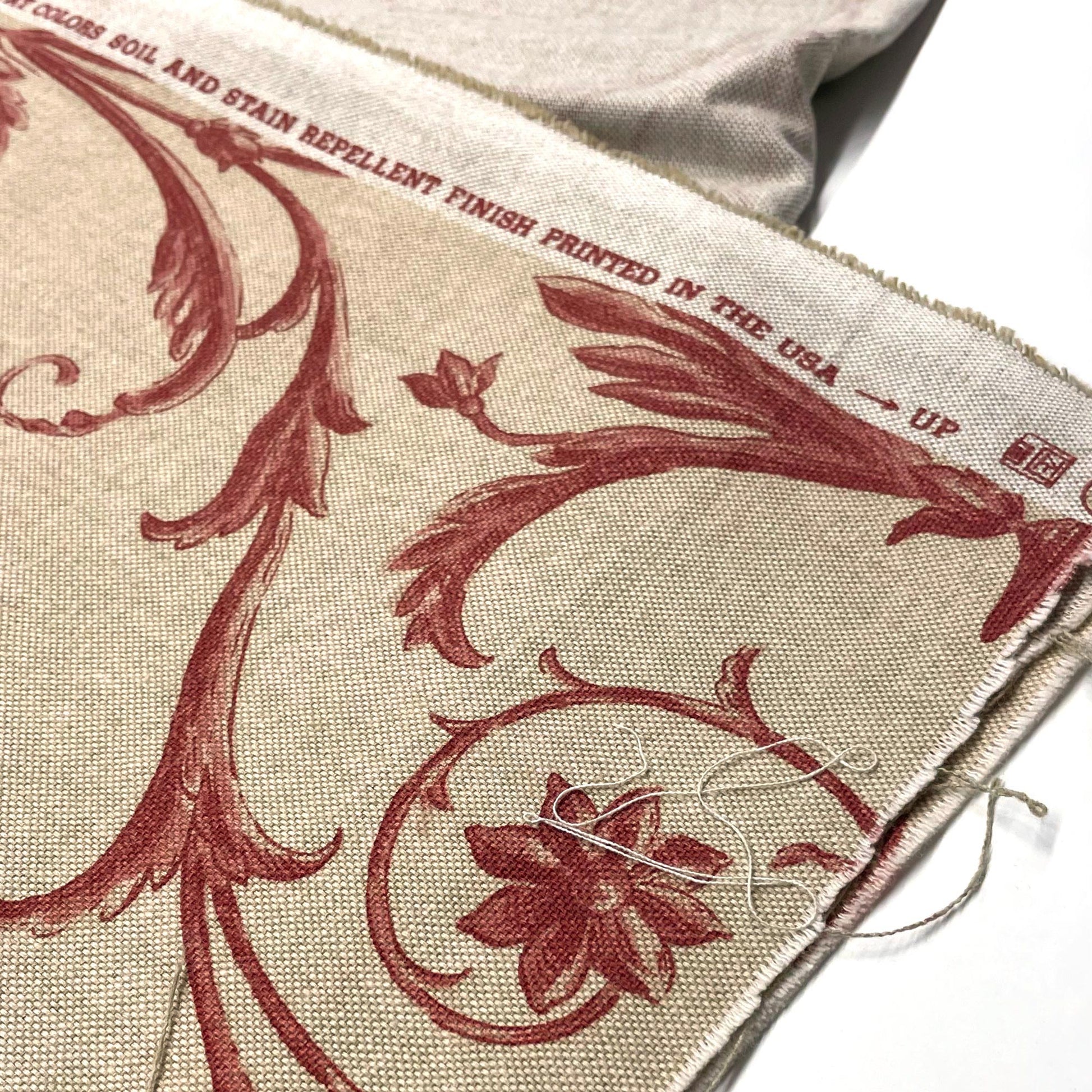 Printed text on the selvage edge regarding the soil and stain repellent finish, shown alongside the red botanical details.