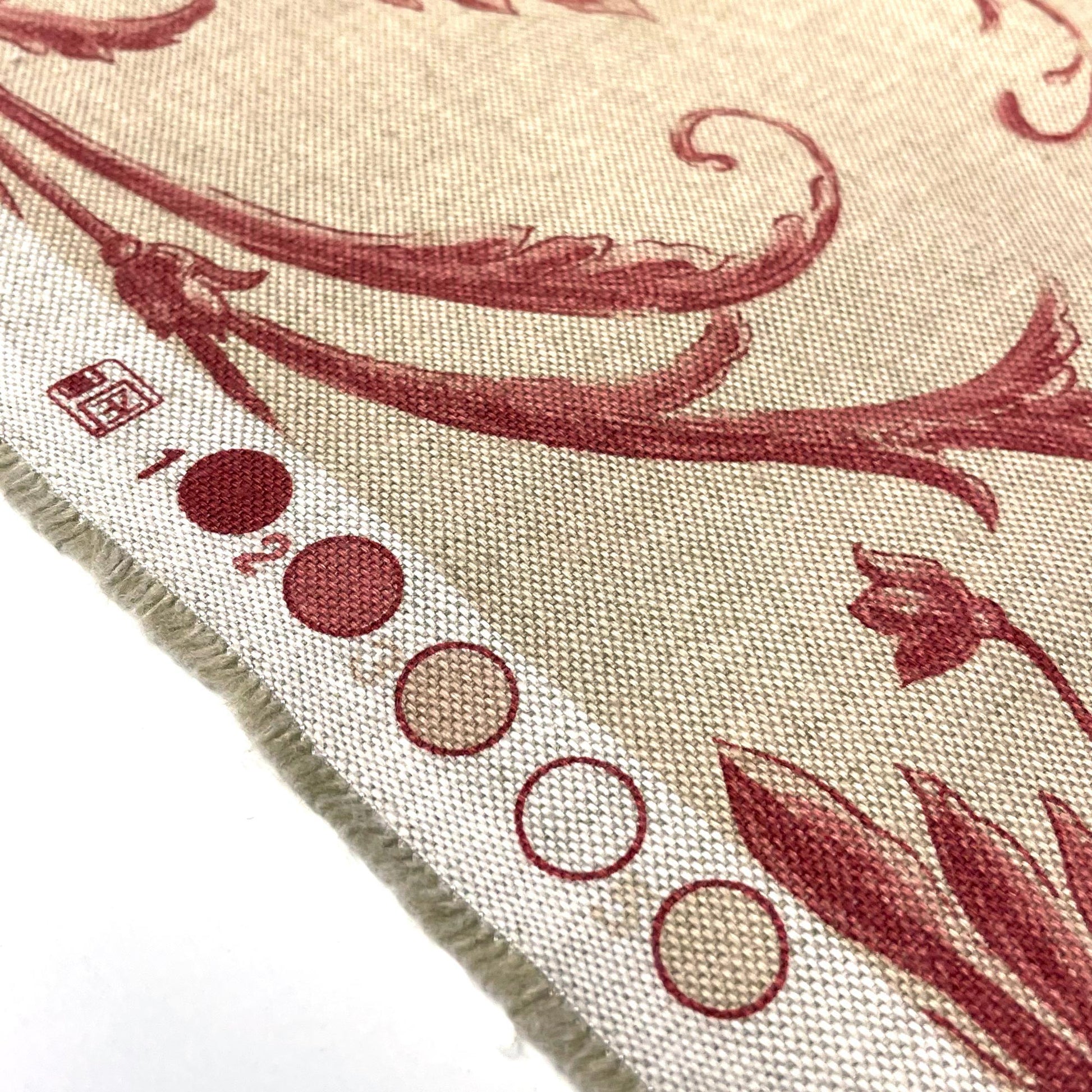 Row of circular color registration marks in varying shades of red and beige beside the crimson floral pattern on the fabric's edge.