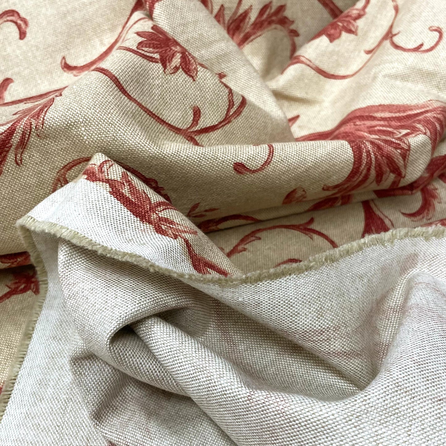 Sweeping yardage of traditional botanical fabric, highlighting the flexible drape of the material and the unprinted white reverse side of the textile.