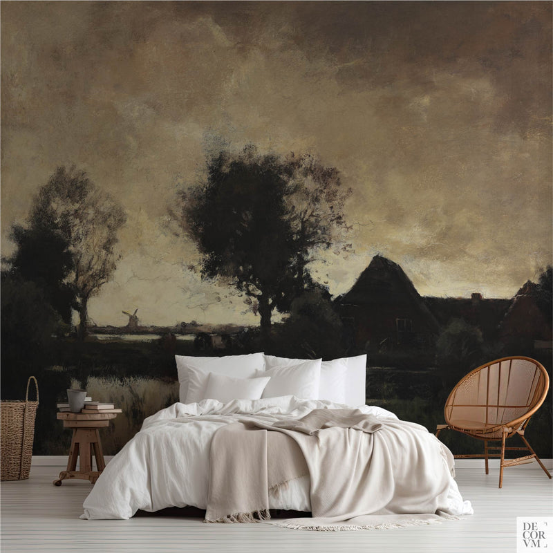 Dark academia landscape wall mural in moody bedroom with white linen bed, rattan chair, and wooden side table styled in vintage Dutch farmhouse aesthetic