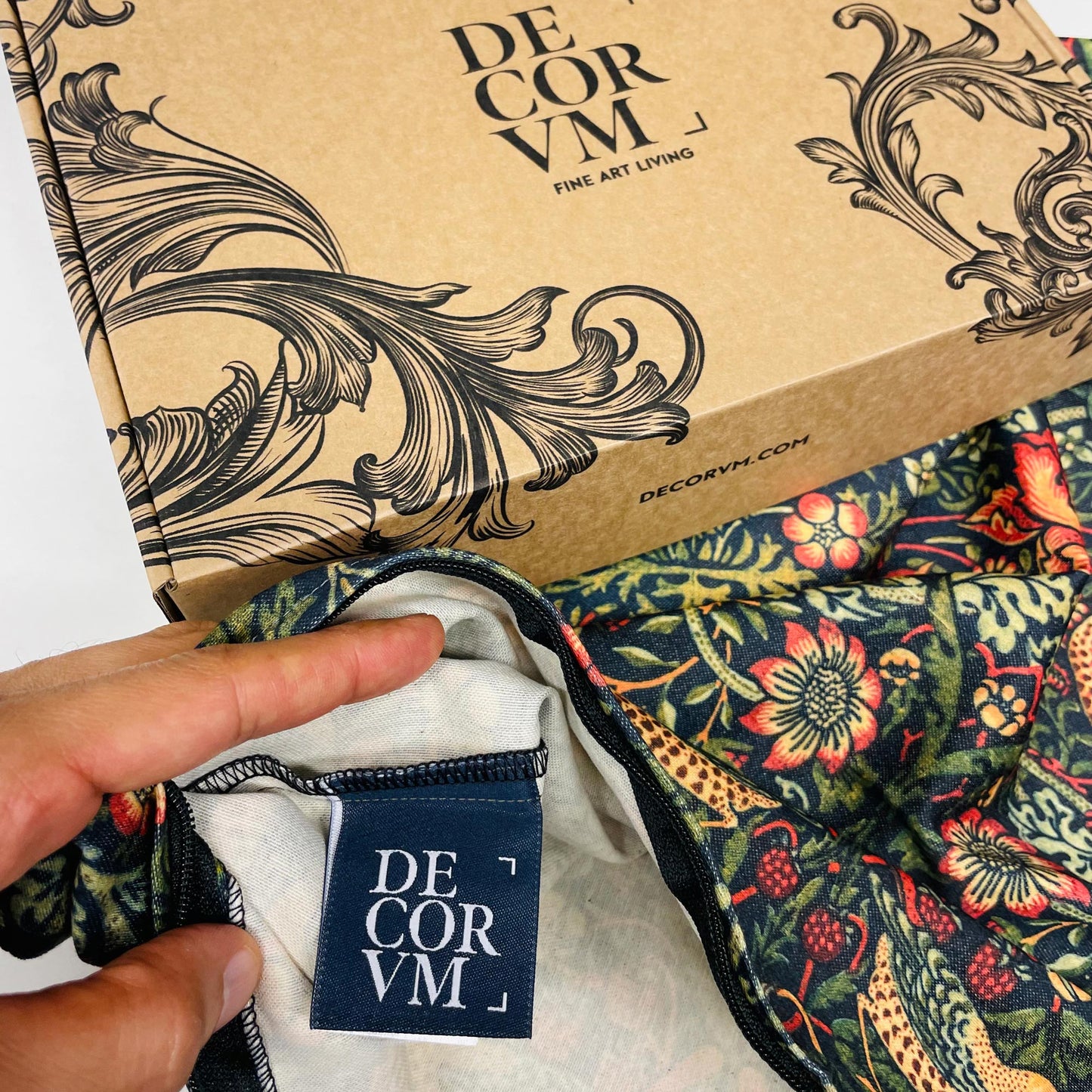 Dark green Strawberry Thief pillow cover beside a Decorvm presentation box.