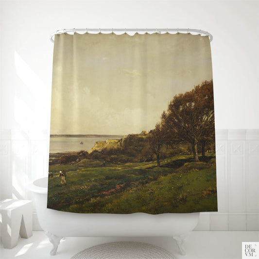 French seaside landscape shower curtain hanging on a curved rod over a white clawfoot bathtub in a bright modern bathroom — vintage coastal painting with green meadow, autumn trees, and calm sea