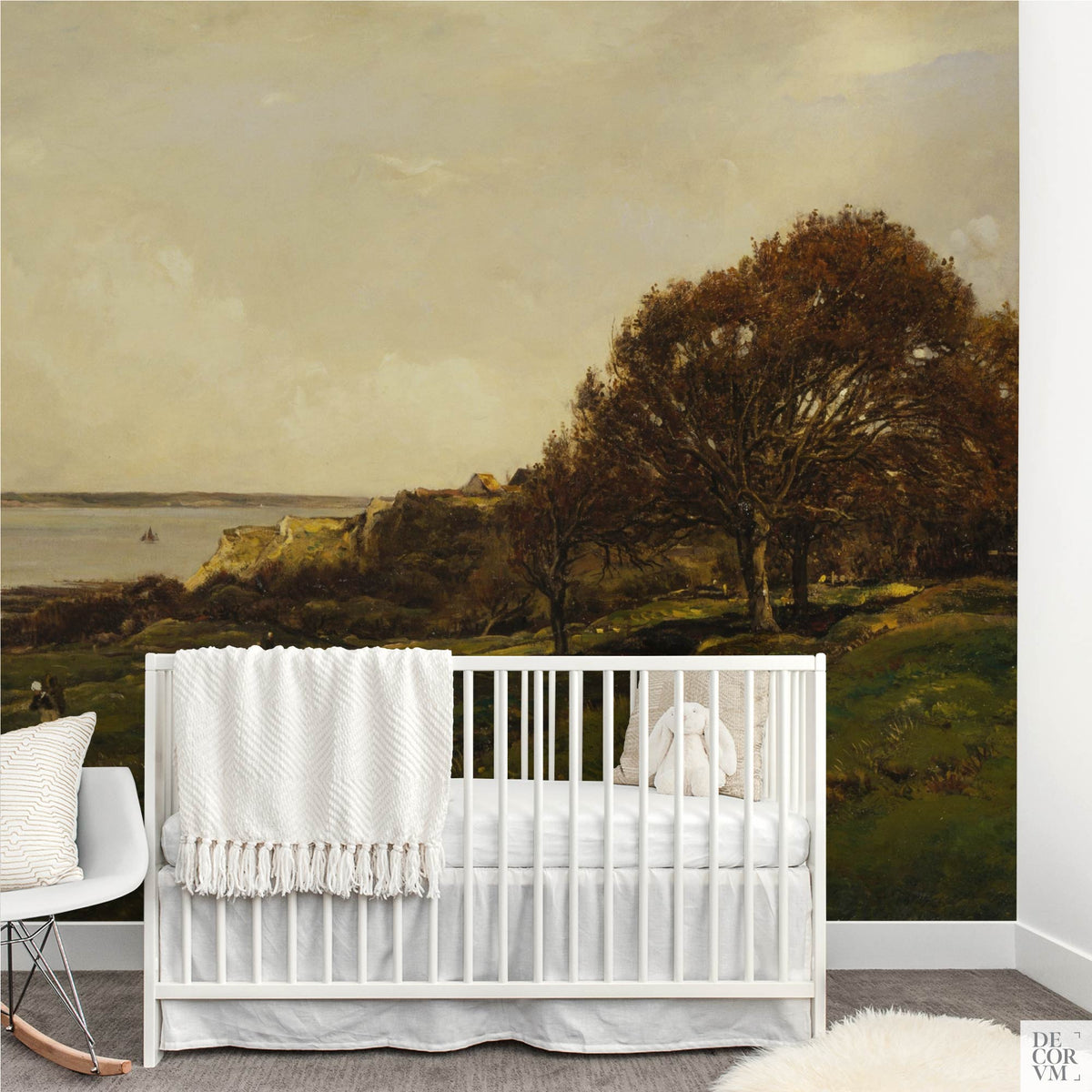 French seaside landscape wallpaper mural in a nursery with white crib and rocking chair — vintage painting of coastal cliffs, trees, and sea