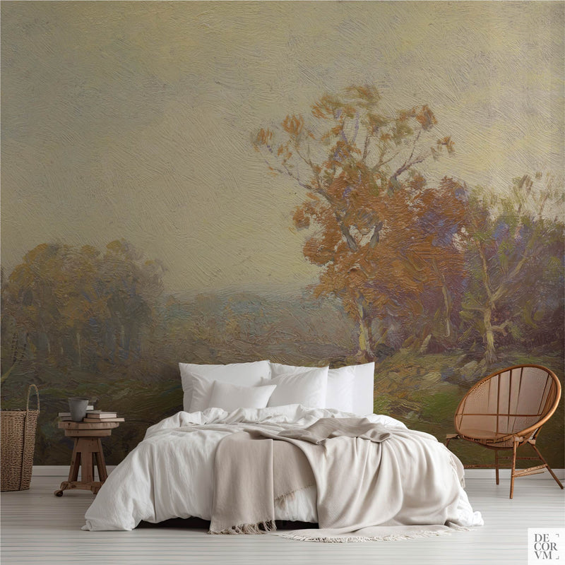 Golden autumn landscape wallpaper mural in a bedroom with white bedding and rattan chair — impressionist painting with golden-orange tree and misty hills