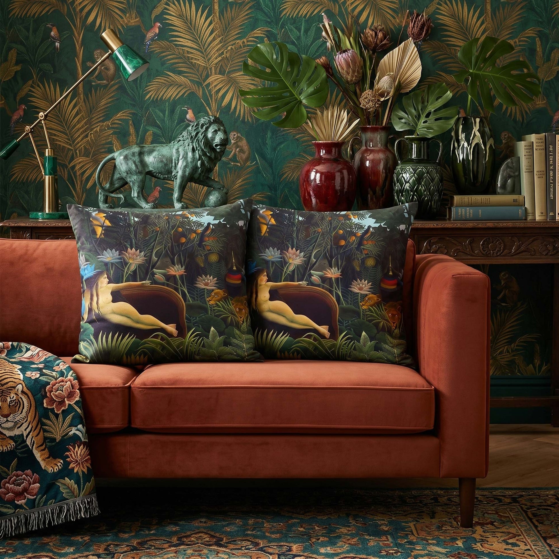 Pair of Henri Rousseau The Dream throw pillows on a rust velvet sofa with dark jungle wallpaper, a lion statue, and a tiger blanket by Decorvm.