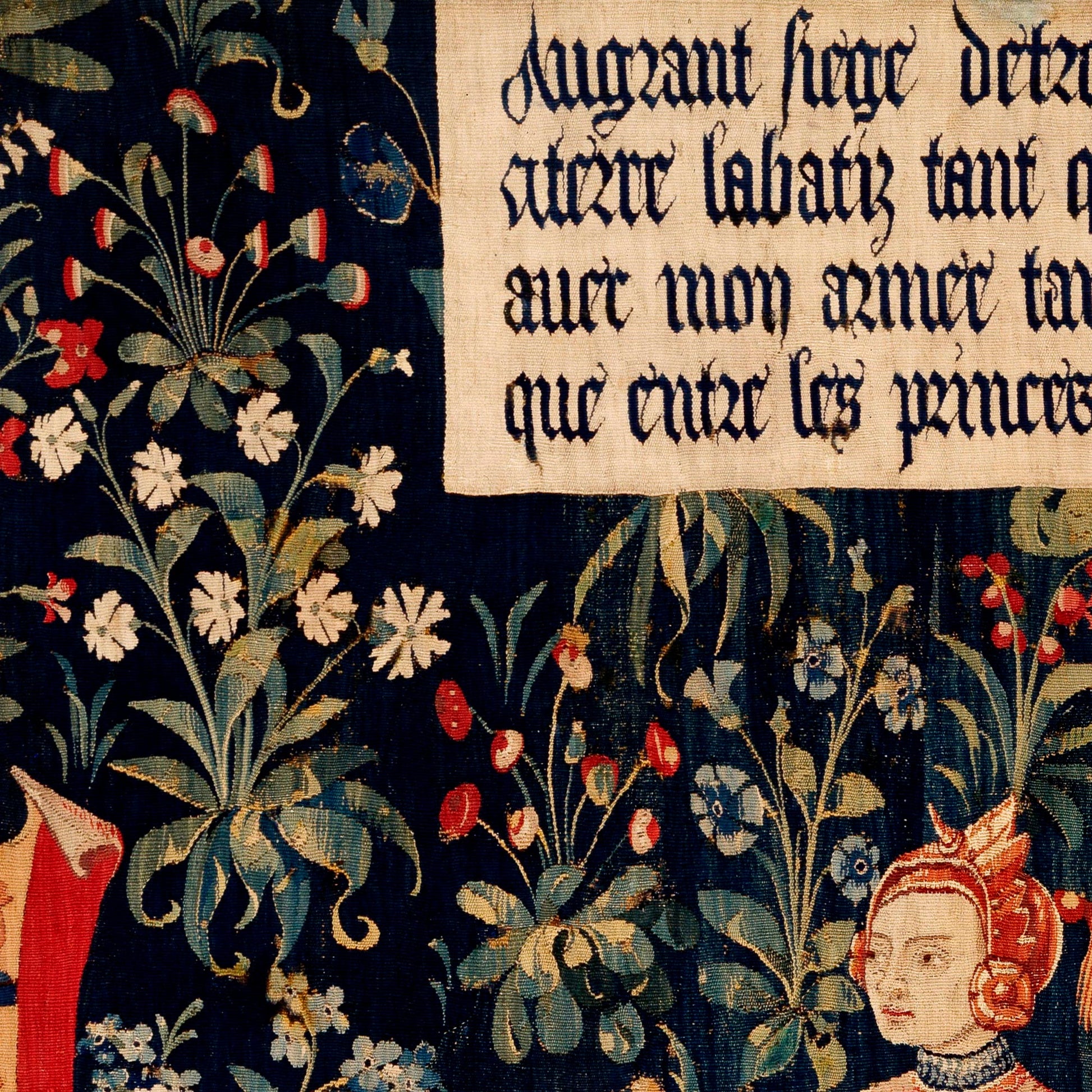 Gothic blackletter banner above the crowned Penthesilea in crimson armour on a dense navy botanical field — detail of the late 15th-century Flemish millefleurs tapestry.