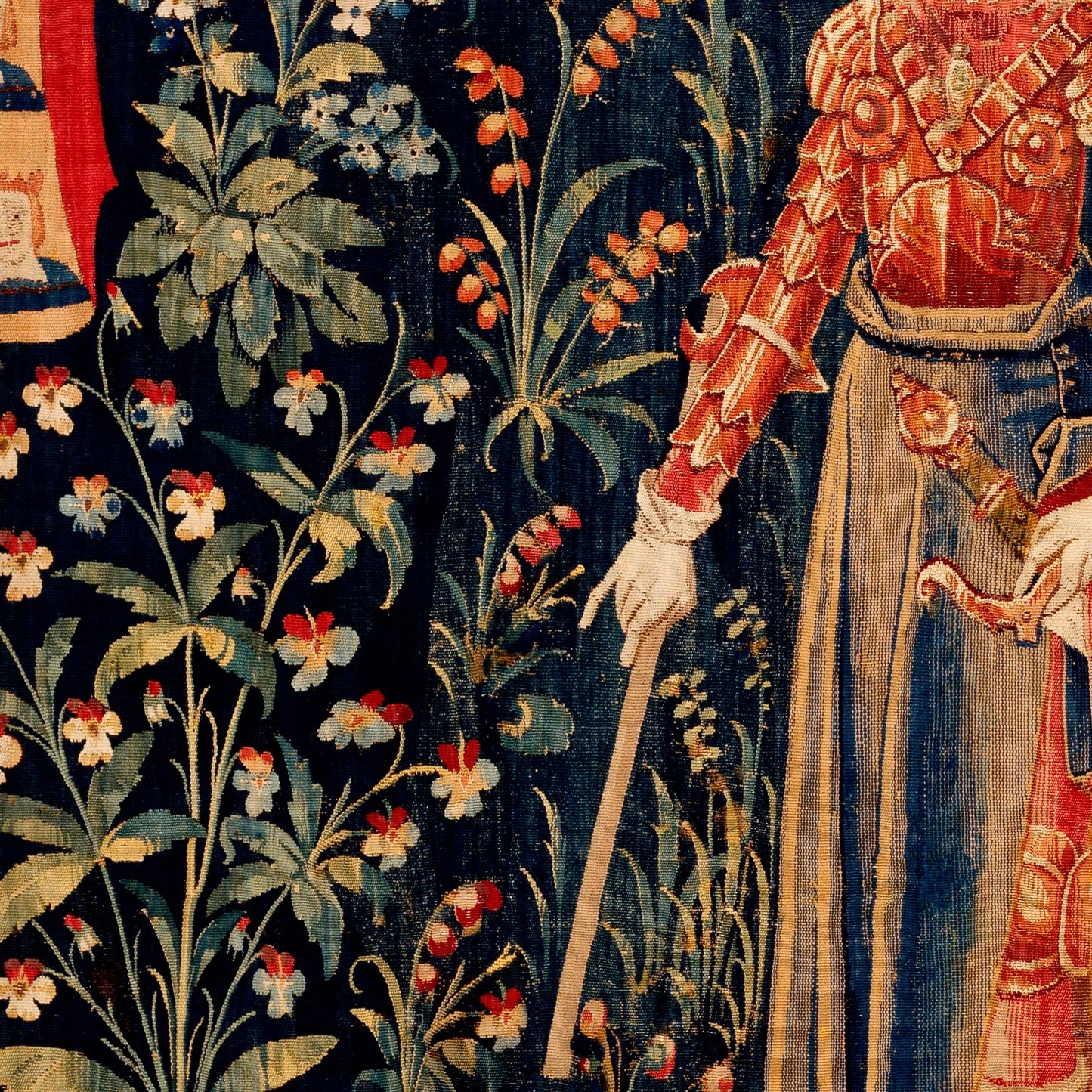 Ornate red and gold armour with white gauntlets and a heraldic banner — detail of the late 15th-century Flemish millefleurs Penthesilea tapestry.