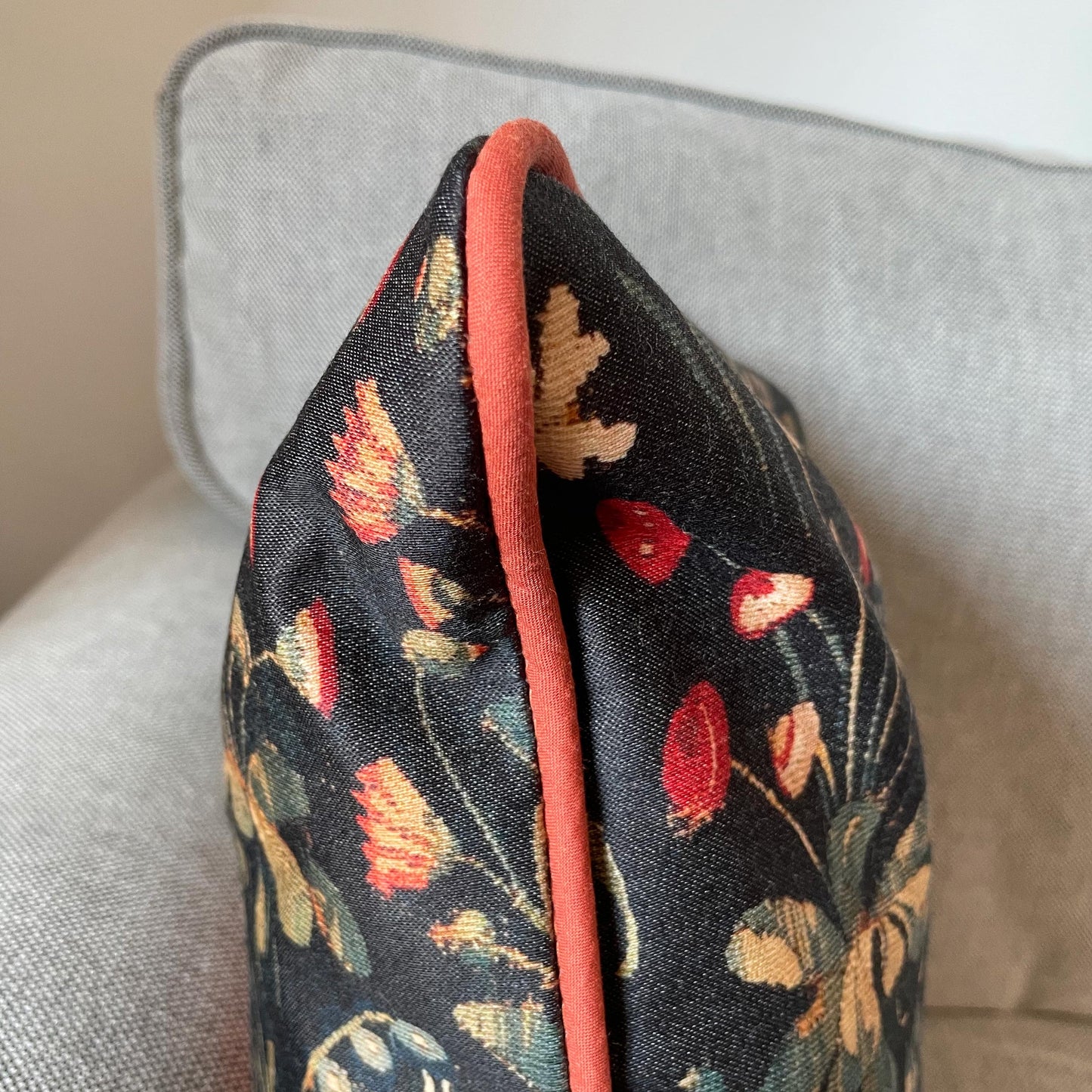 Side profile of the Medieval Amazon Queen cushion cover, showing the plush insert, woven medieval floral design, and red piping finish.