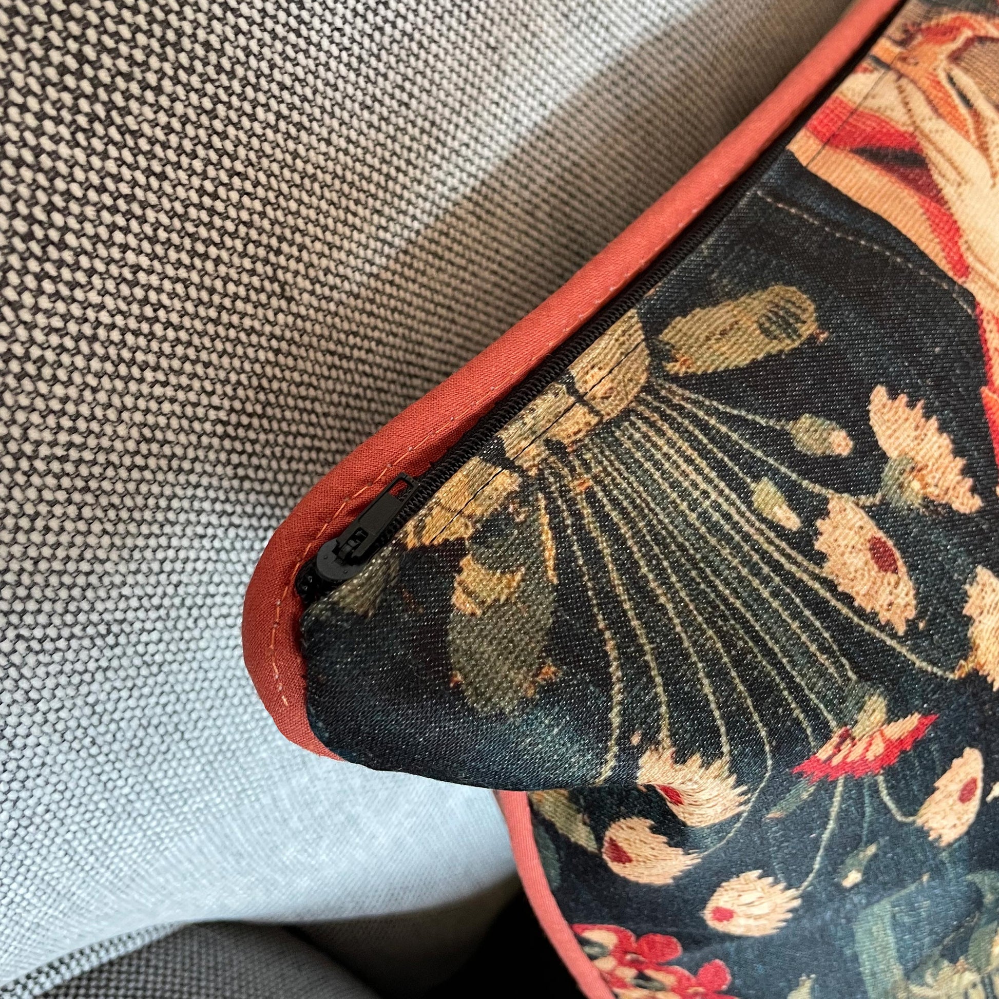 Detail of the discreet hidden zipper closure next to the elegant red corded piping on the Medieval Amazon Queen cushion cover.