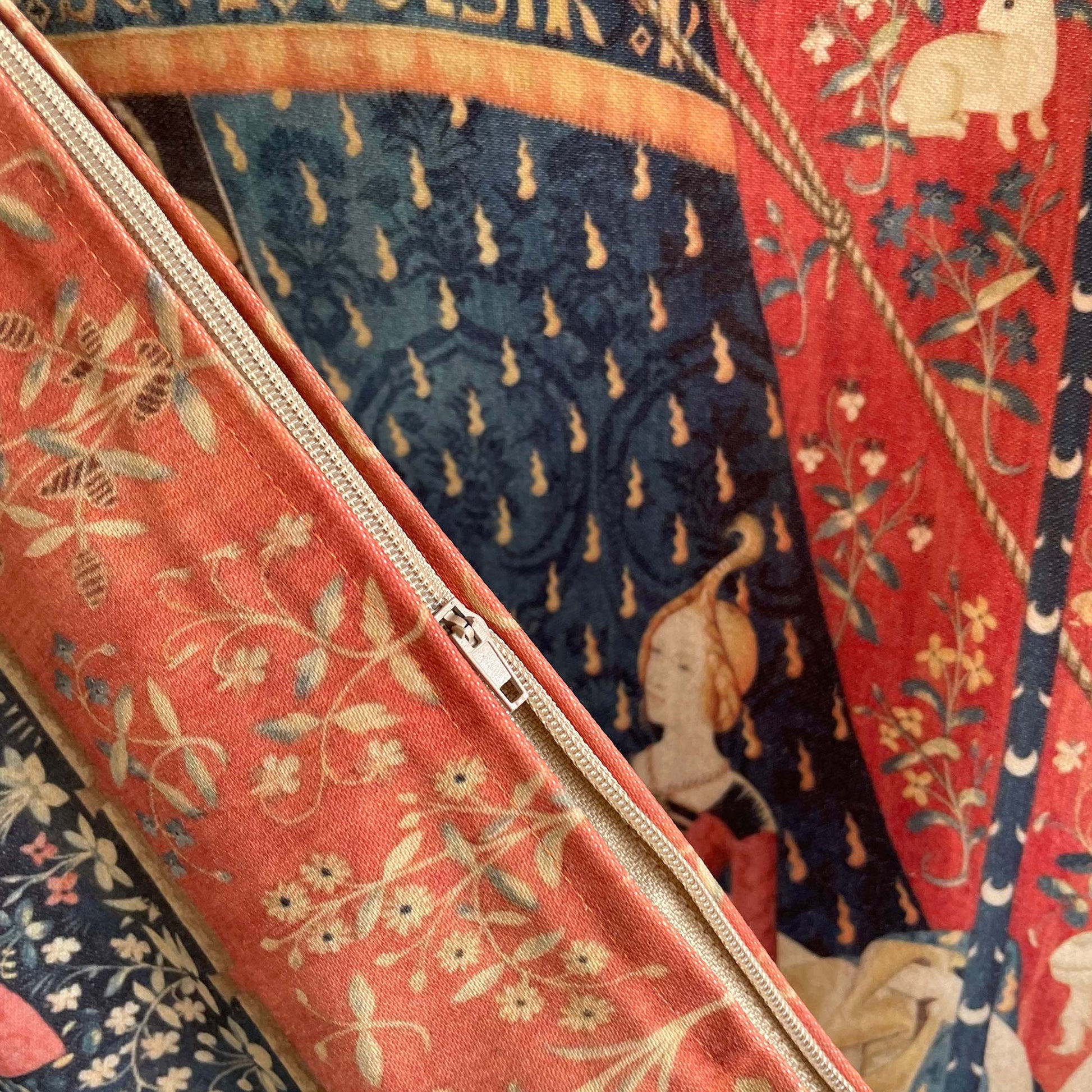 Close-up of the hidden beige zipper stitched along the seam of the Lady and the Unicorn cushion cover — durable fabric and medieval French Gothic print.