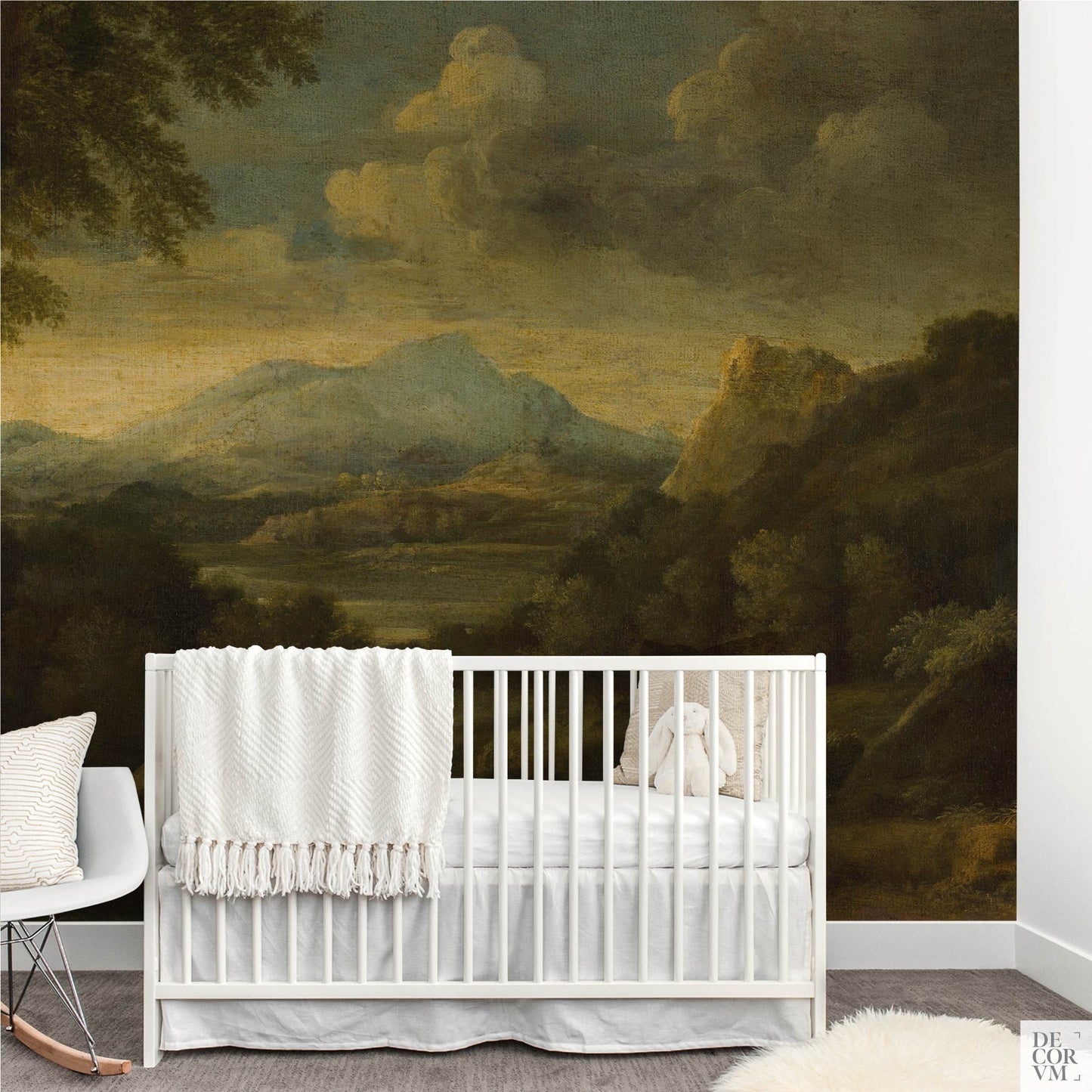Nursery room setup with a white baby crib placed directly in front of the Moody Mountain Landscape Wallpaper Mural — Dark Academia Decor, with a white modern rocking chair to the left.