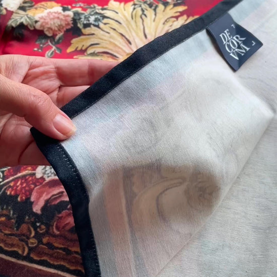 The Arms of Louis XV wall tapestry product video — hands showcasing the flexible cotton blend drape, stitched hem, white backing, and the red and gold French baroque heraldic print.