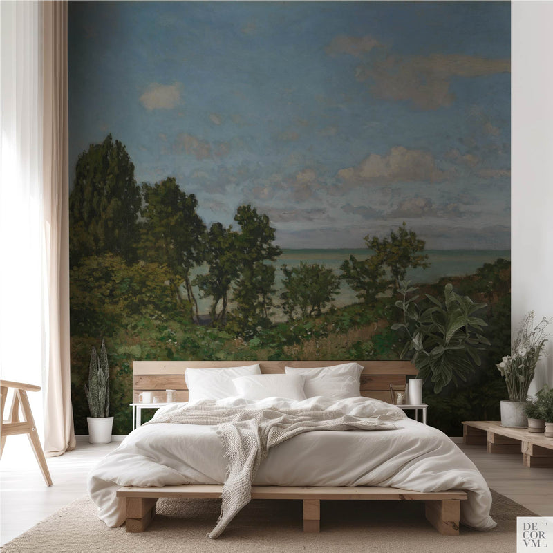 Monet coastal landscape wallpaper mural in an earthy bedroom — 1864 Normandy coast scene with green trees behind a low wooden bed by Decorvm
