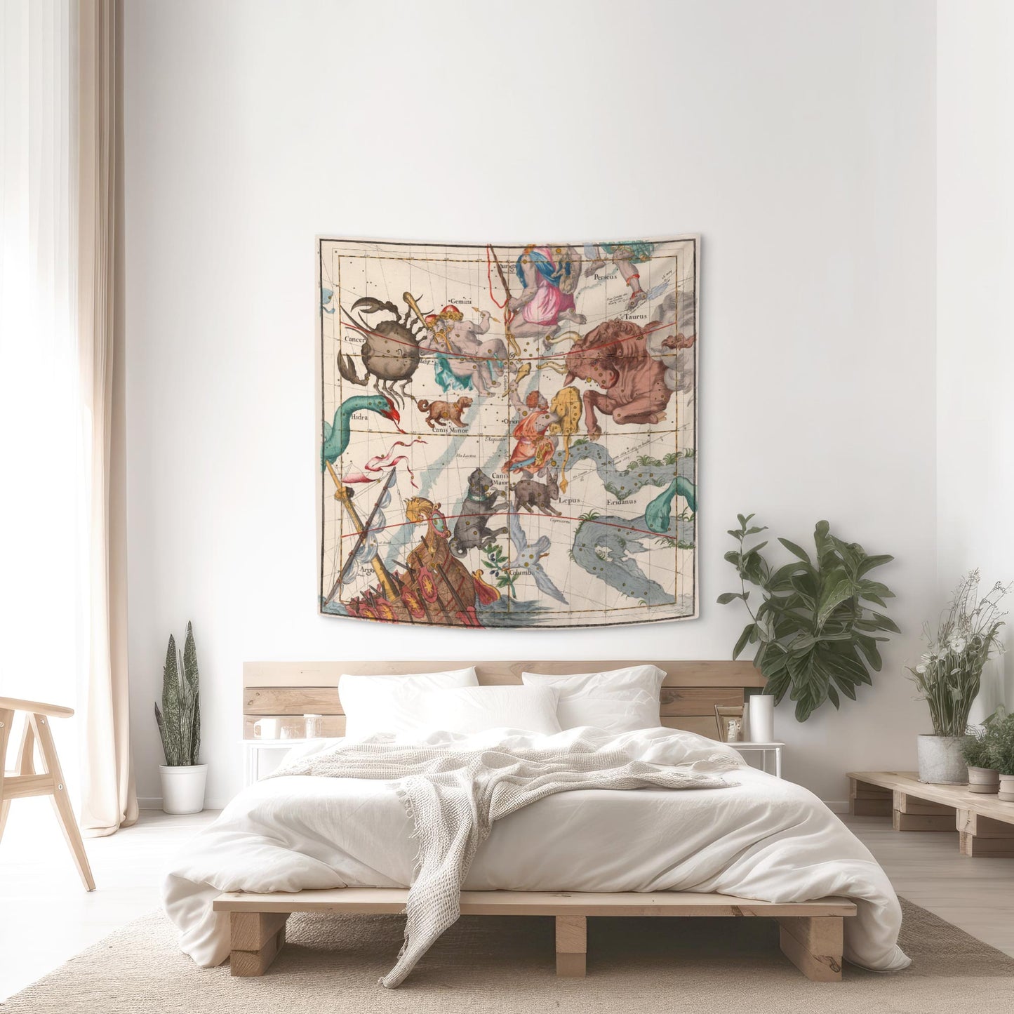 Orion and Taurus celestial map tapestry hung above a wooden platform bed with white linens and indoor plants.
